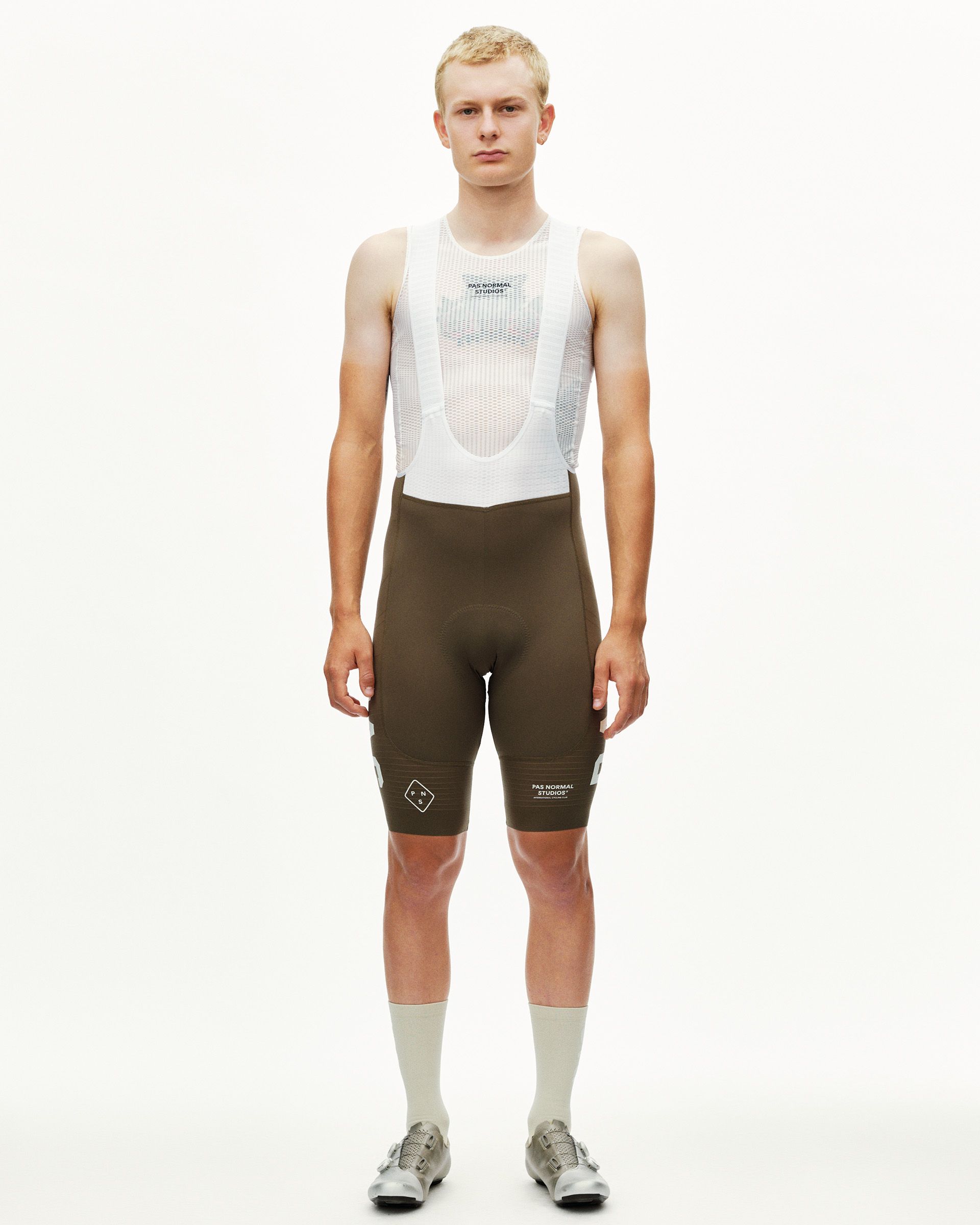 Dark Earth brown PAS Mechanism Pro cycling bibs on model, front view with white mesh bib straps and leg logo print