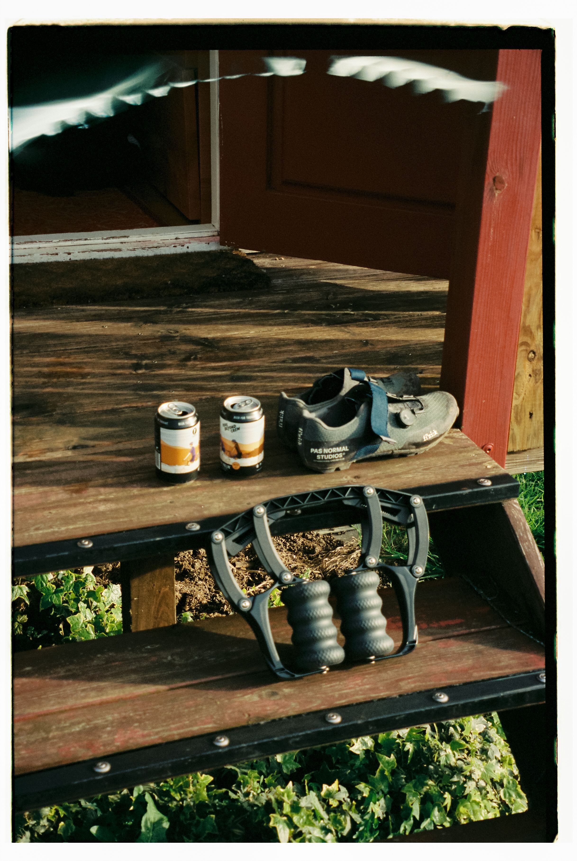 Cycling shoes and recovery accessories arranged on wooden steps with beverages