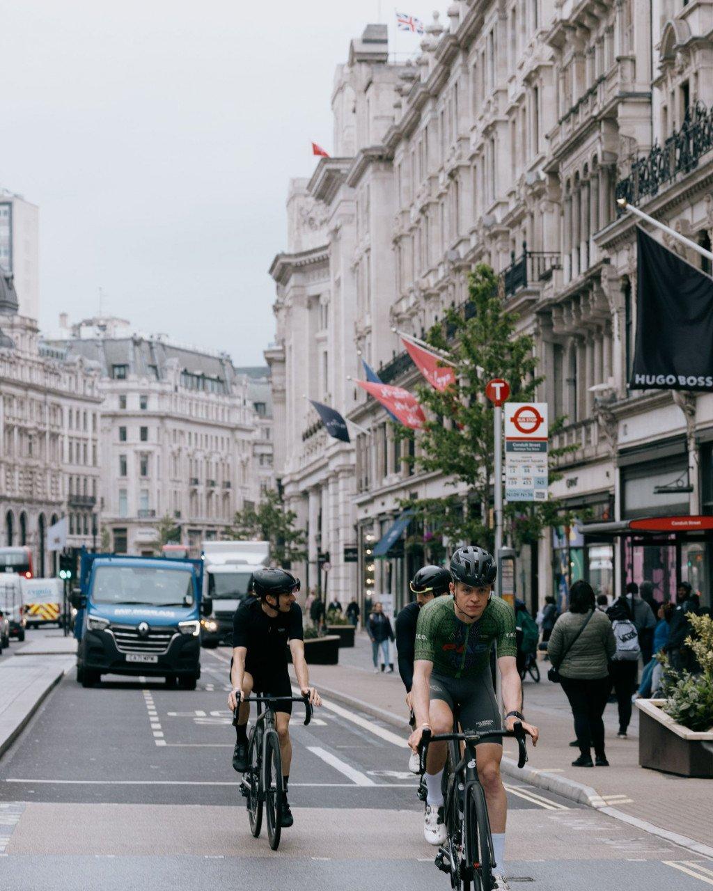 Two cyclists riding time trial bikes on London street in cycling apparel