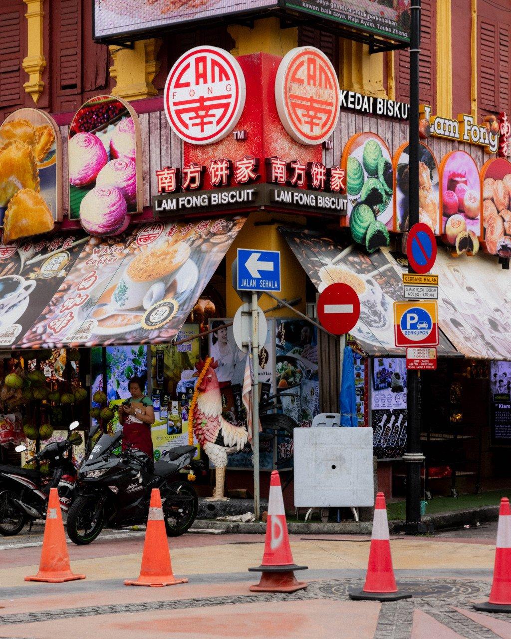 Colorful street scene in Singapore with traditional shophouse, local signage, and traffic cones
