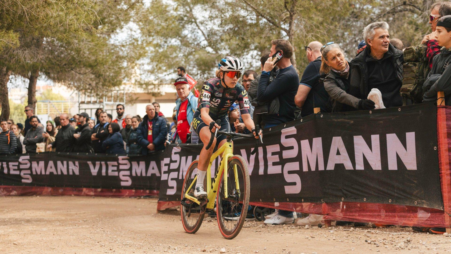 Cyclist racing through dusty course past spectators at competitive cycling event