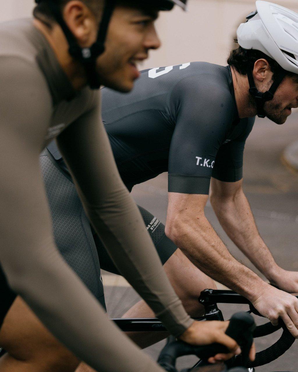 Models wearing grey cycling jerseys with white lettering during indoor training session