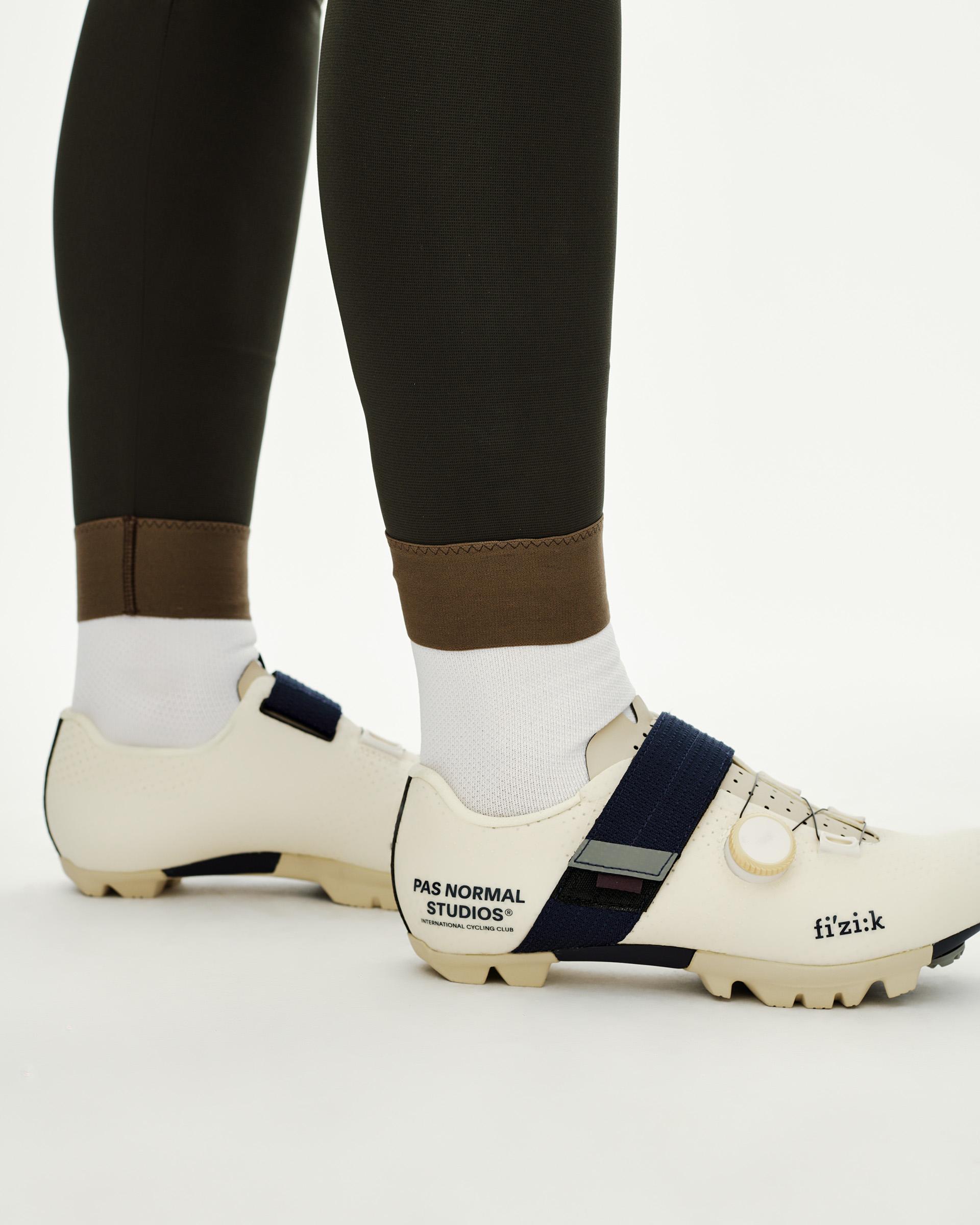 Dark Olive Women's Escapism Long Cargo cycling bibs, side detail on model showing contrast brown ankle cuff