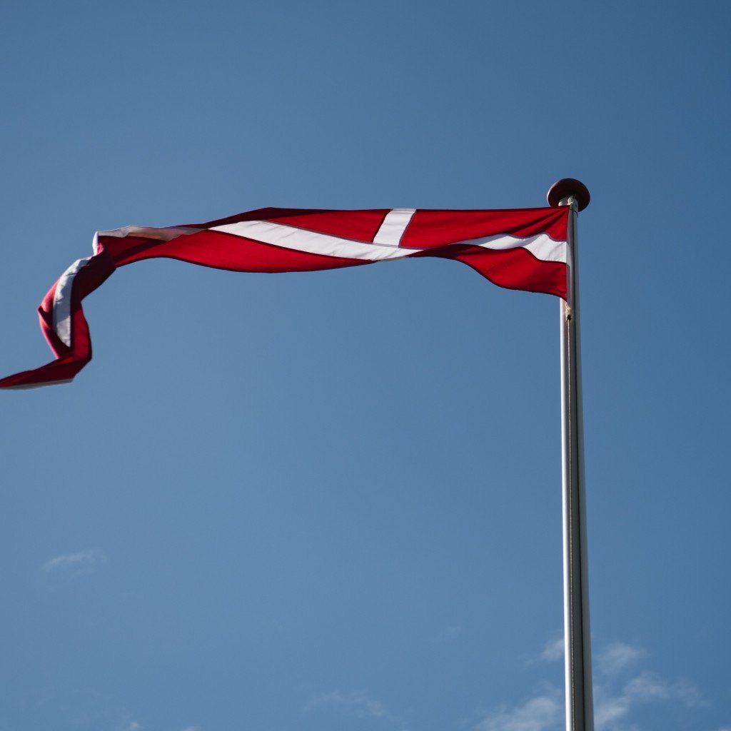 Danish flag waving on flagpole against blue sky