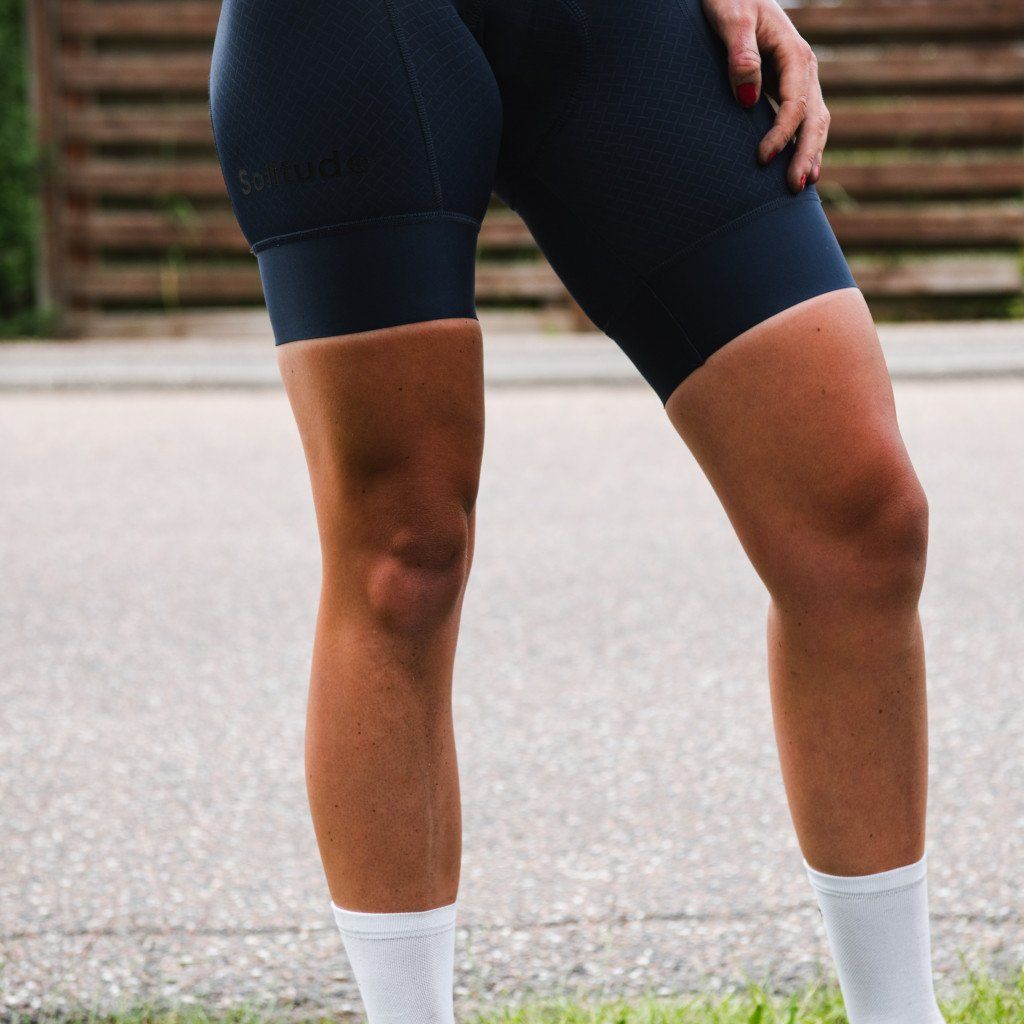 Model wearing navy blue cycling shorts with white socks, showing close-up of legs and fit