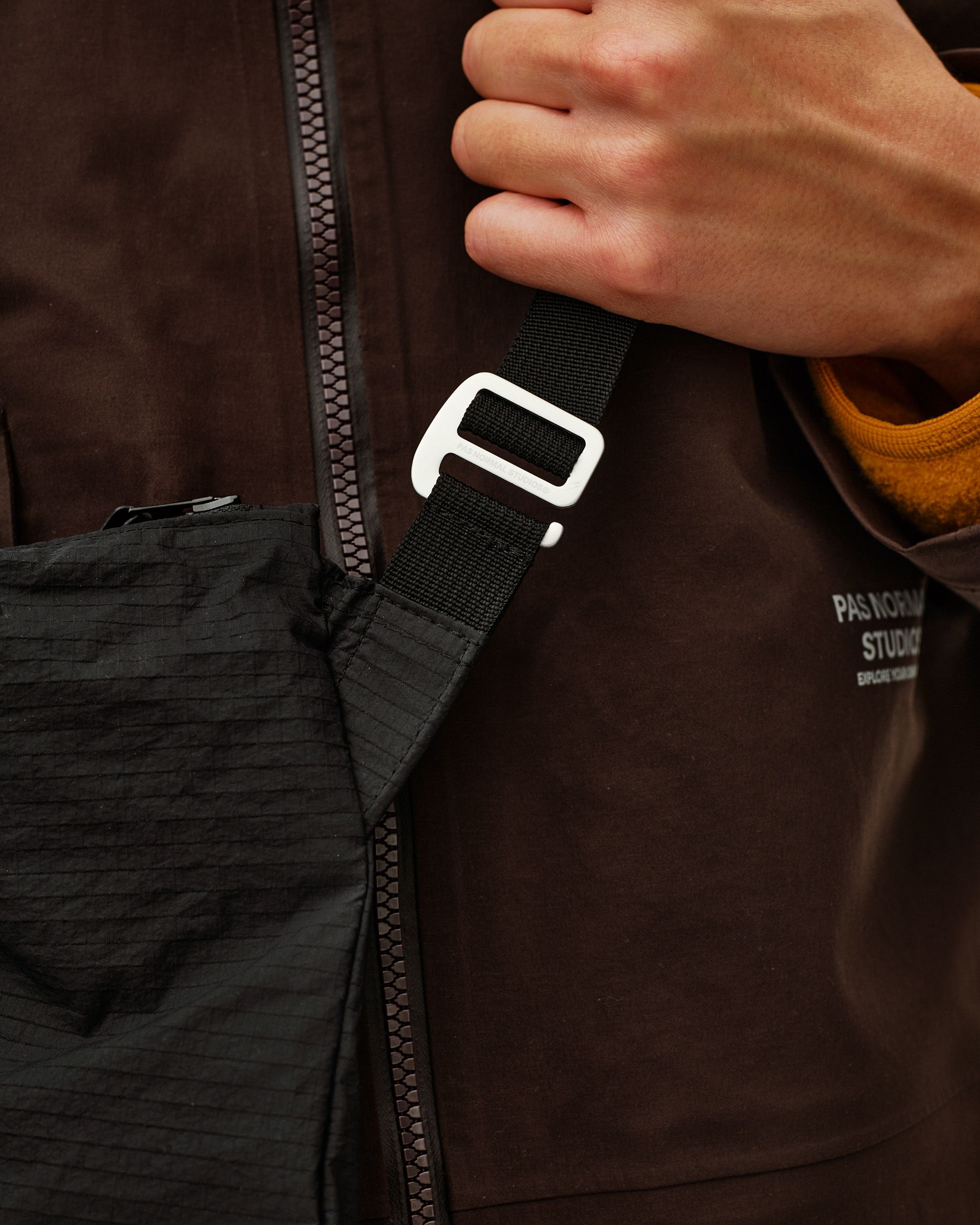 Black Off-Race Tech Musette 2.0 bag, detail view of white branded buckle and black webbing strap on model