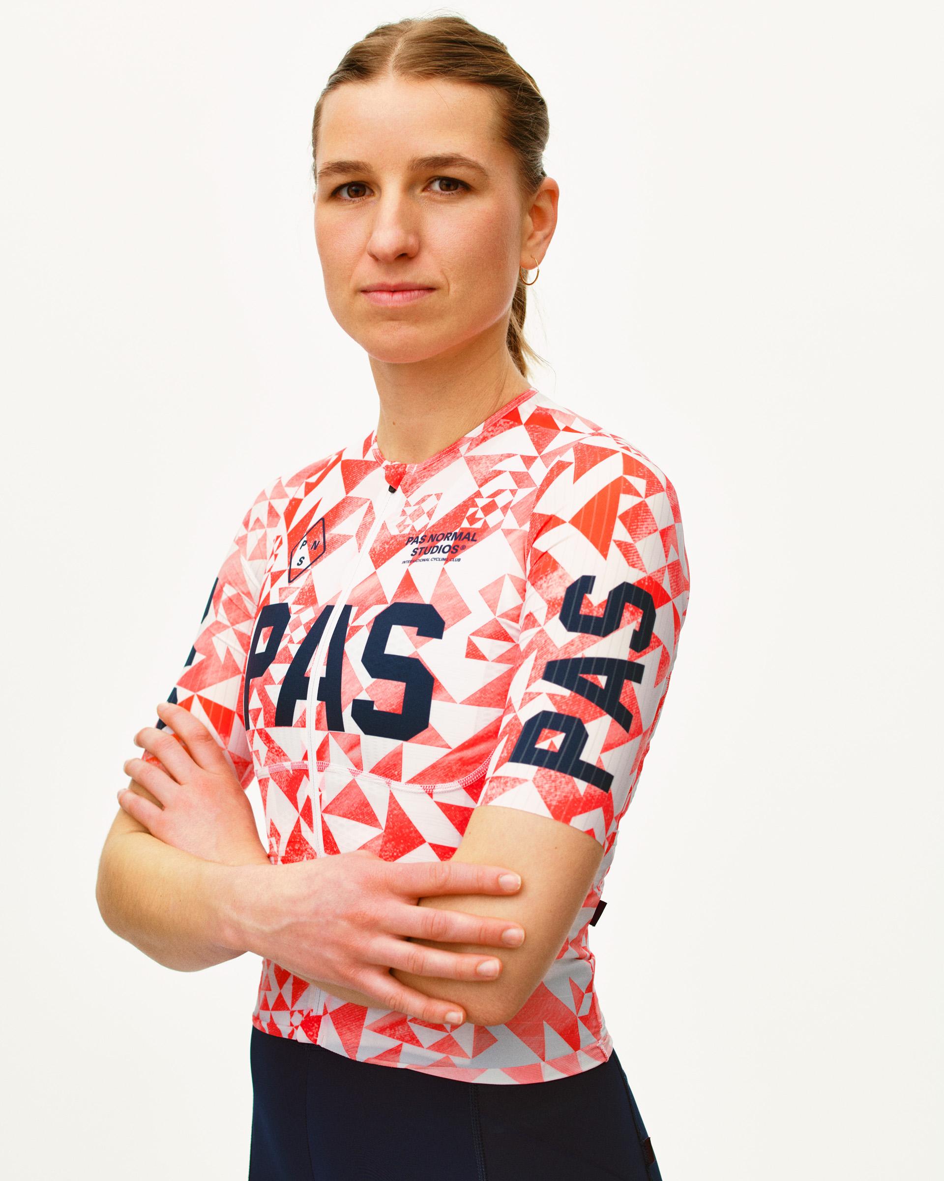 Red PAS Mechanism Pro cycling jersey on model with geometric origami print and navy PAS lettering