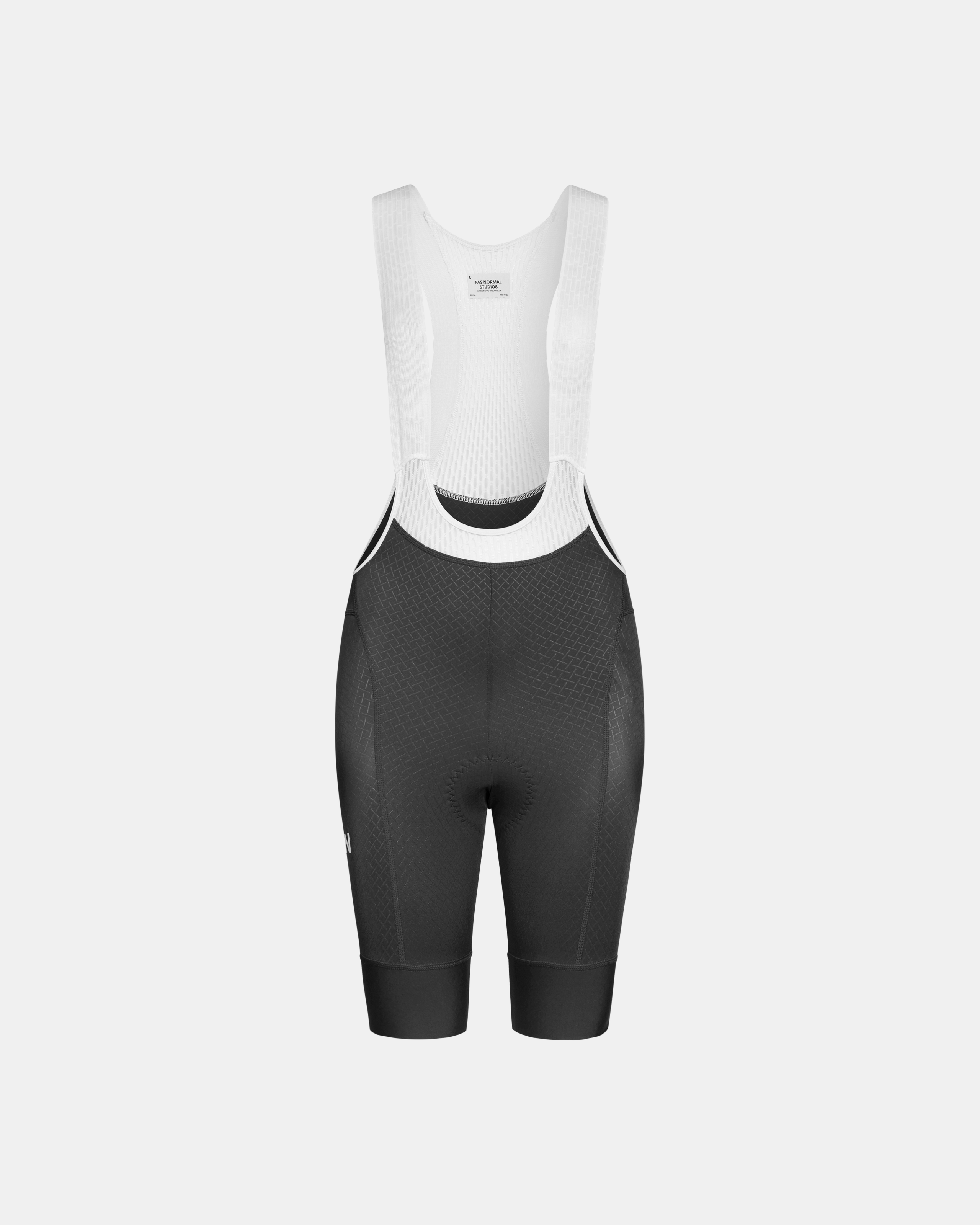Black Mechanism cycling bibs, front flat lay with white shoulder straps and textured leg panels
