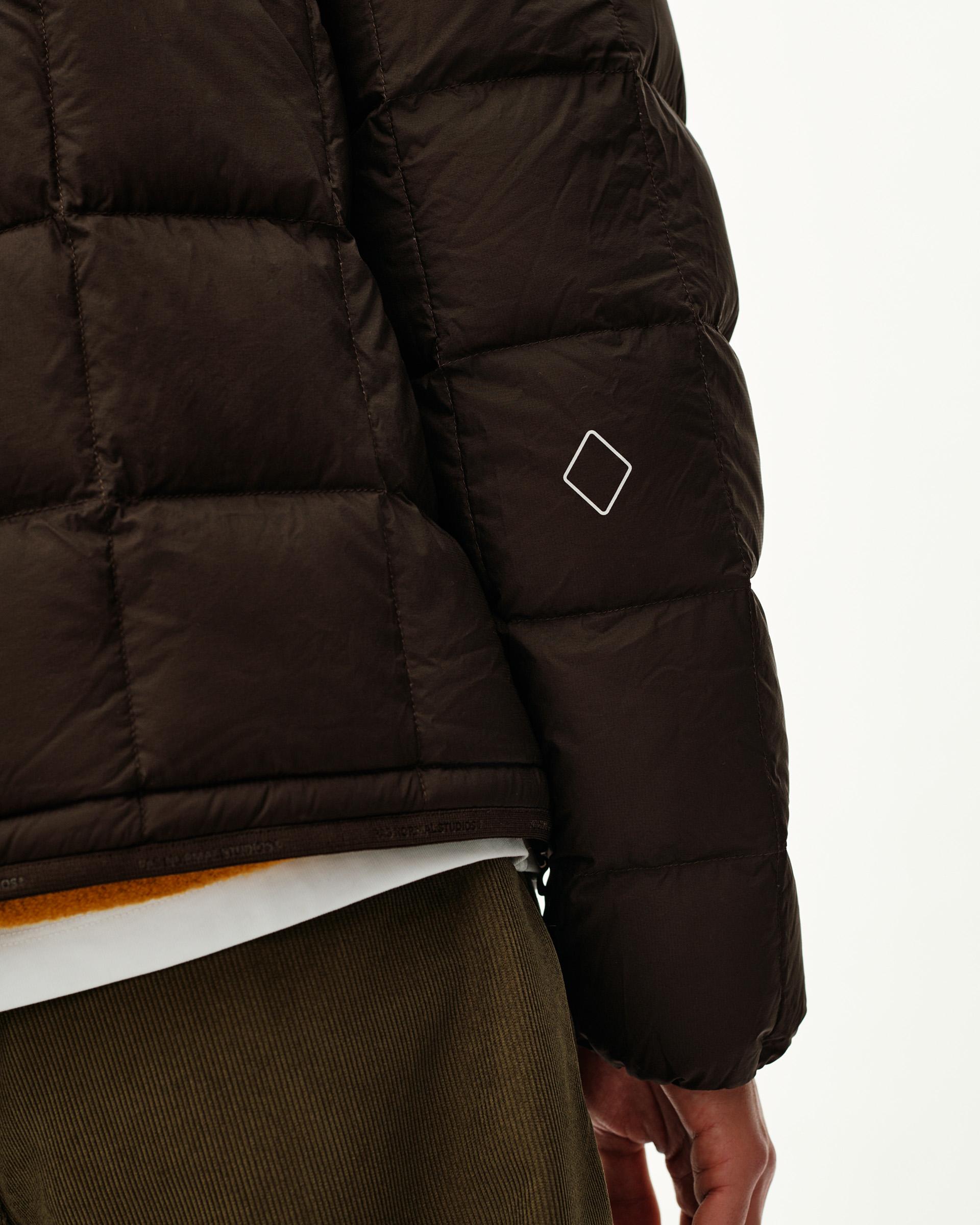 Dark Coffee brown Off-Race Down Liner jacket, side detail on model with quilted panels and white diamond logo on sleeve