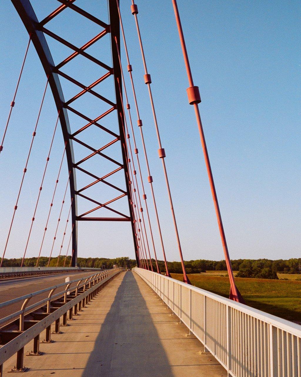 Red suspension bridge walkway with cycling path under blue sky