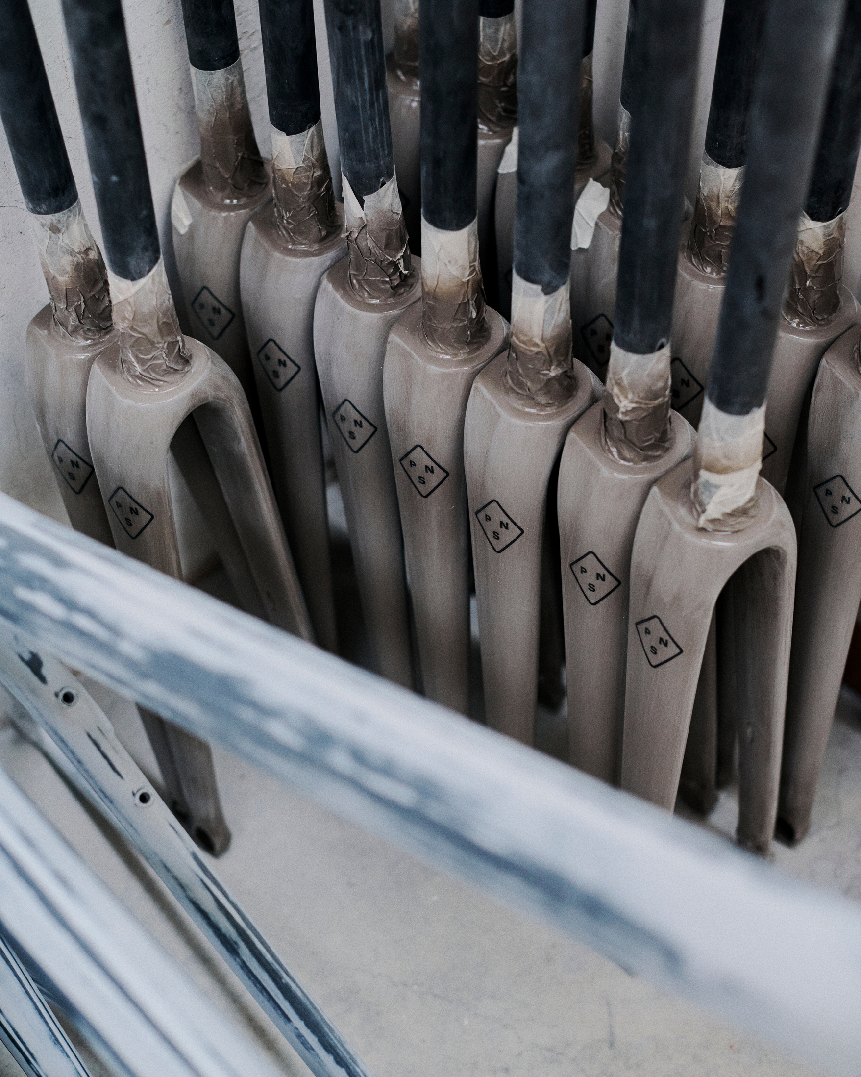 Multiple grey Colnago bicycle forks with black diamond logos arranged in manufacturing rack