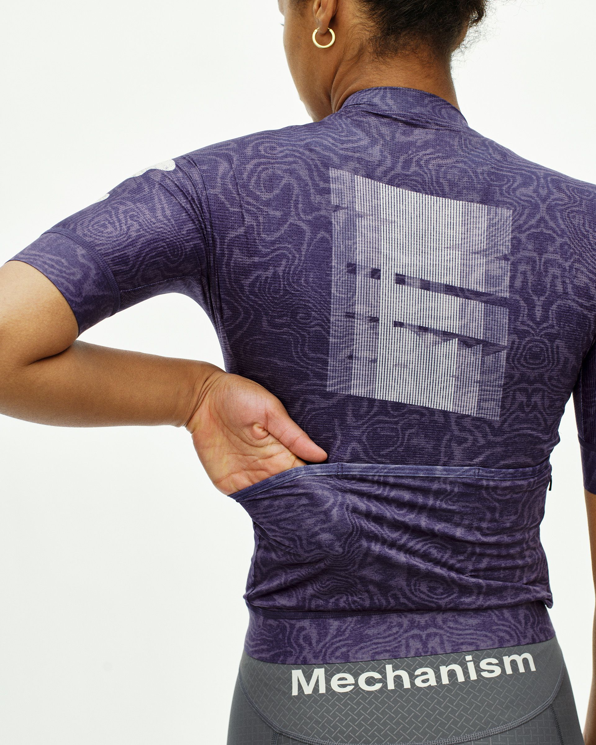 Purple Mechanism women's cycling jersey, rear view on model with tonal wave print and graphic back panel