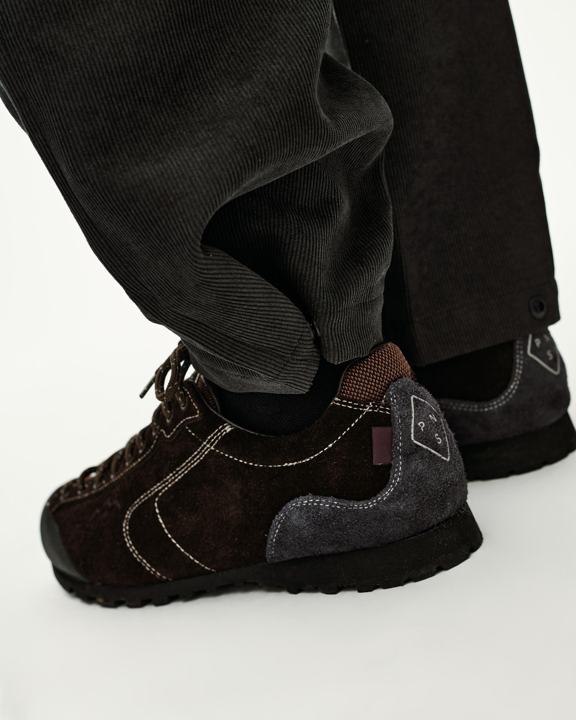 Black Off-Race Corduroy Pants on model, side detail view with ribbed cuffs and brown suede sneaker