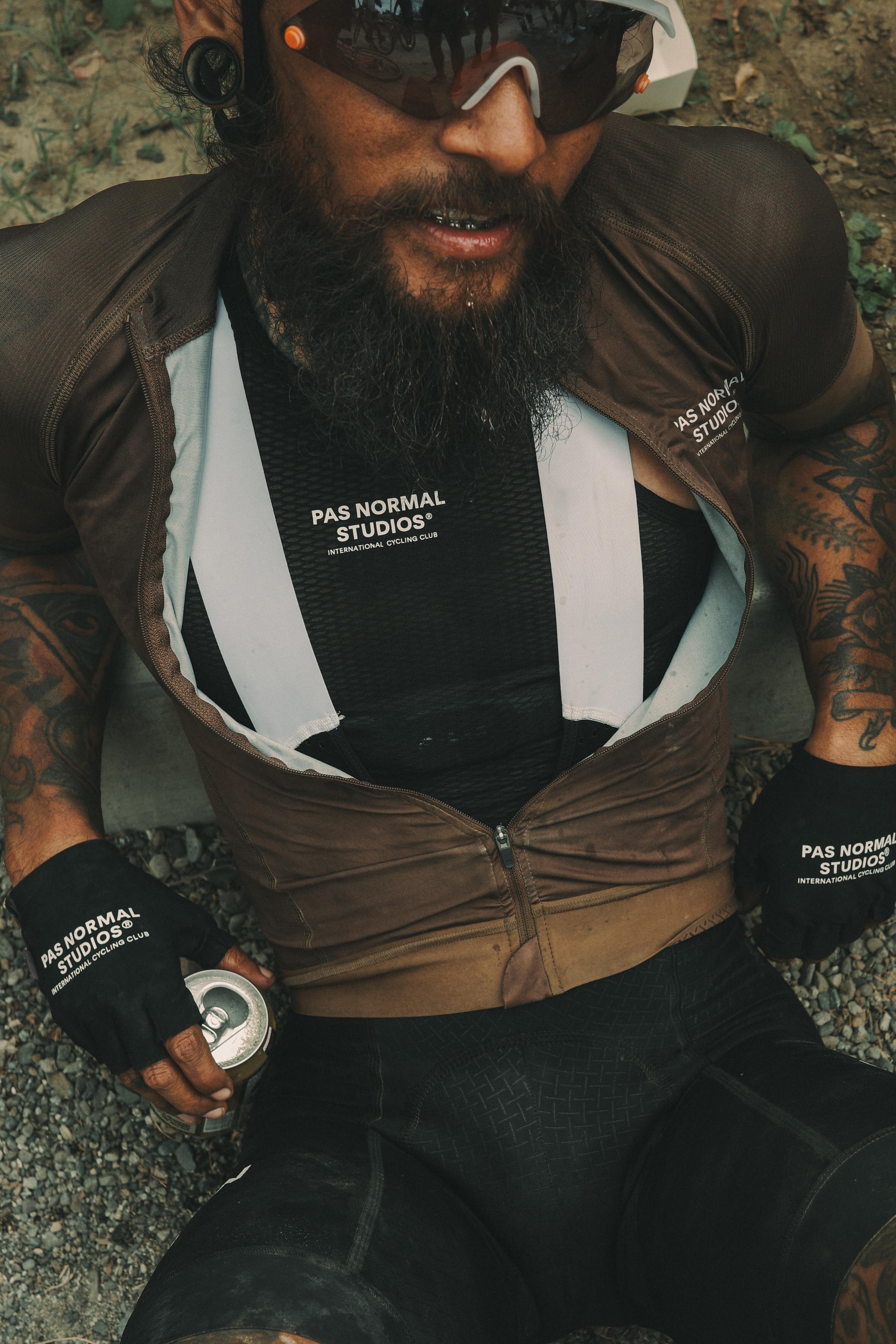 Model wearing black base layer with logo, dark green windbreaker, and matching gloves outdoors