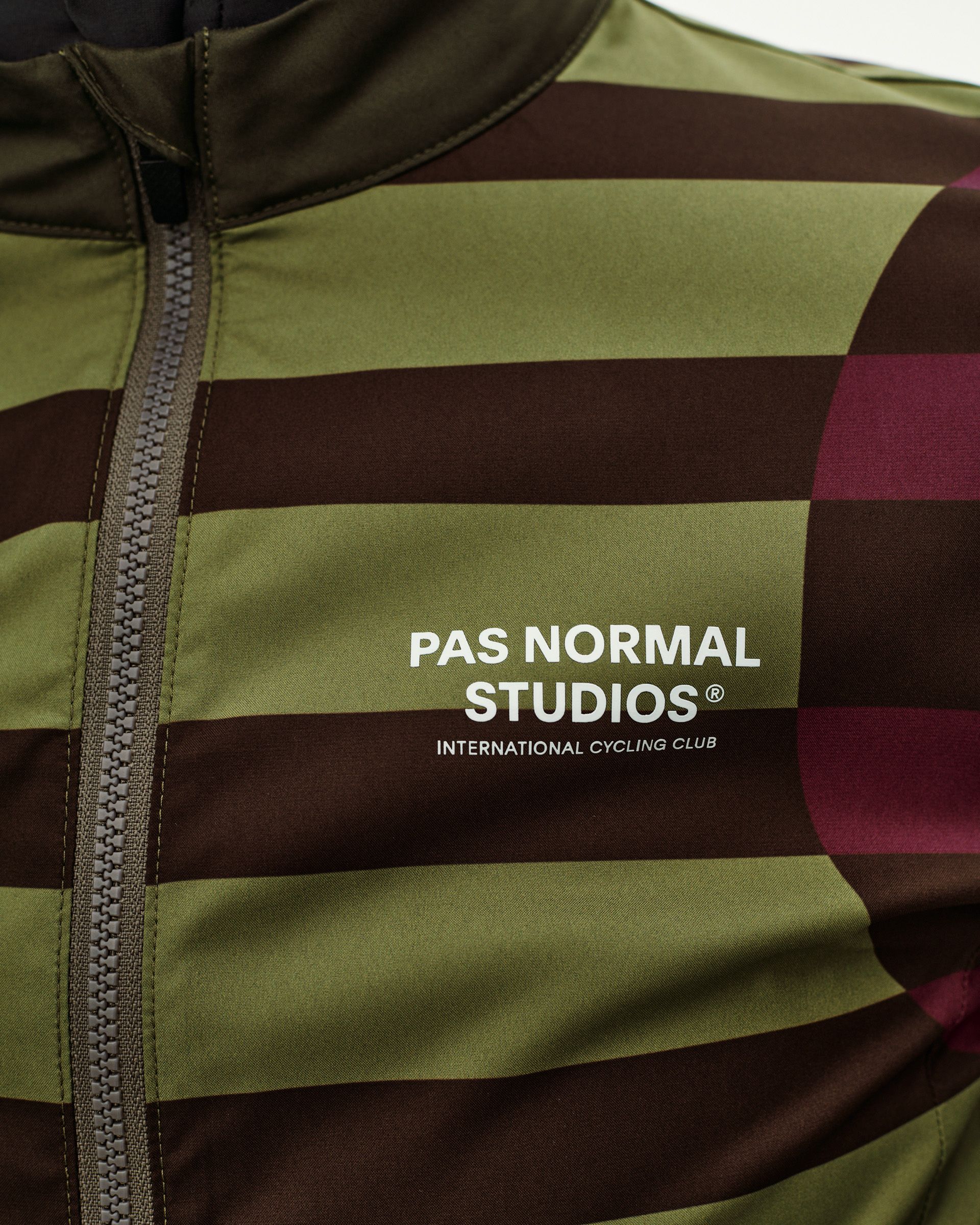 International Green Mechanism Stow Away cycling jacket, front detail with bold stripe print and chest logo