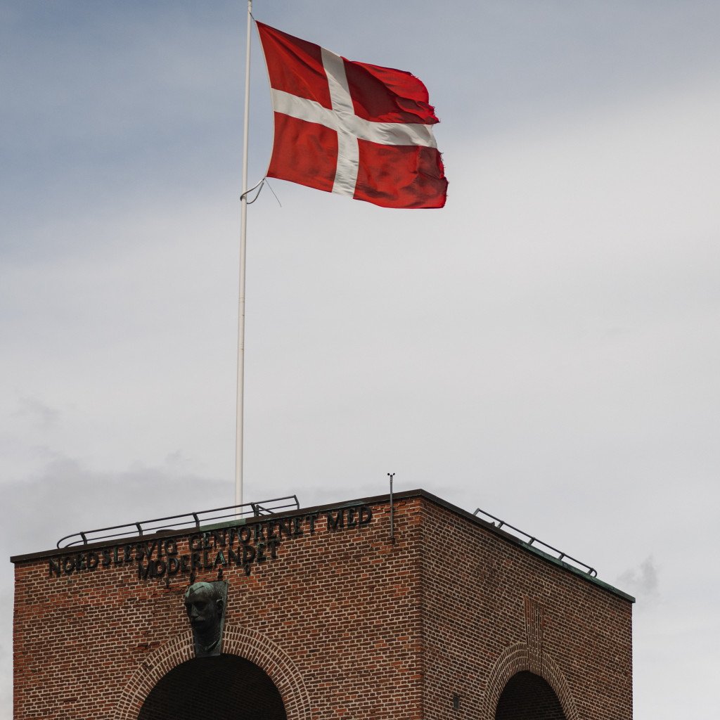 Danish flag flying above brick building with arched architecture