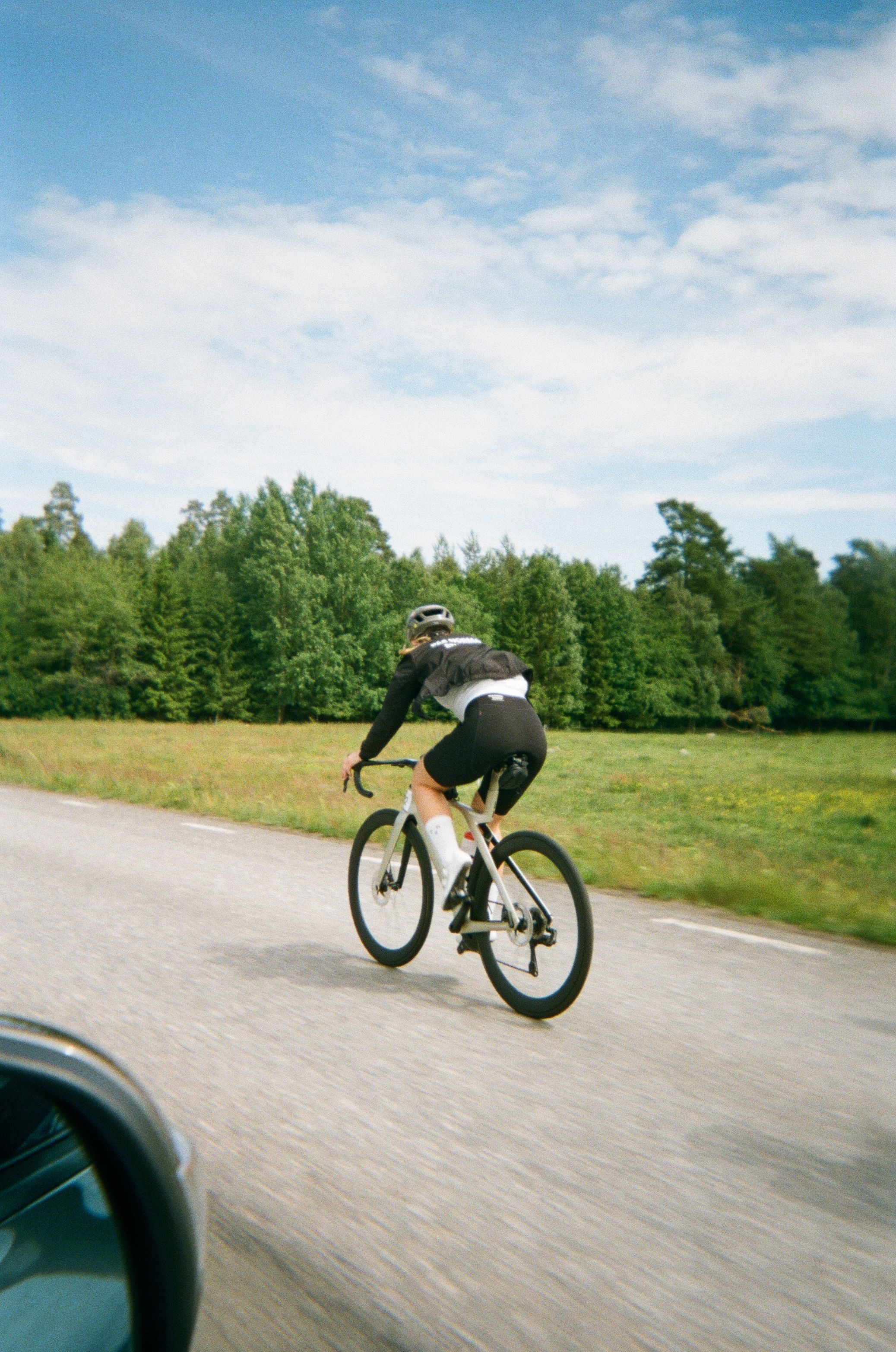 Cyclist in aerodynamic position on time trial bike riding on country road