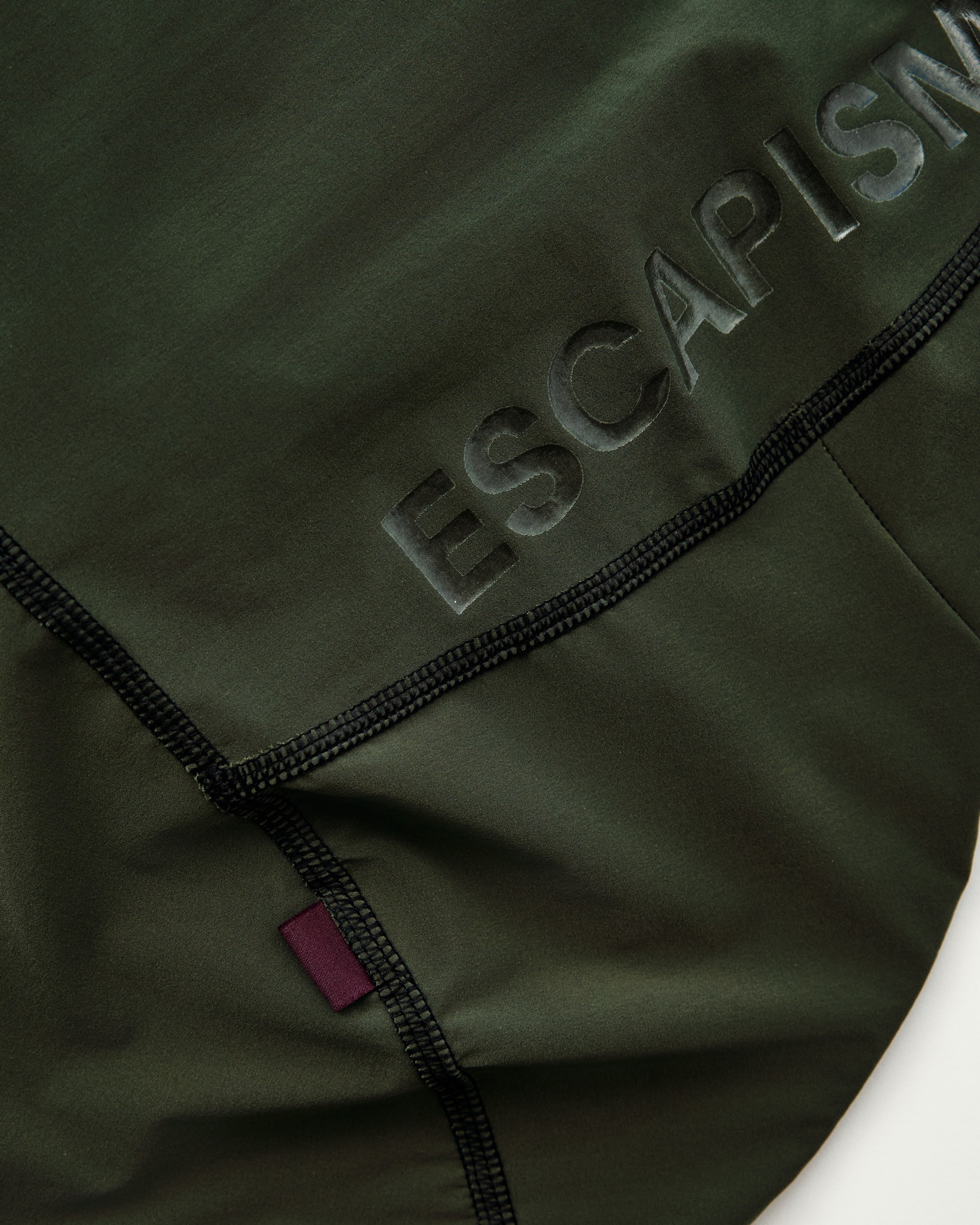Green cycling bib fabric with embossed logo text and black flatlock seaming detail