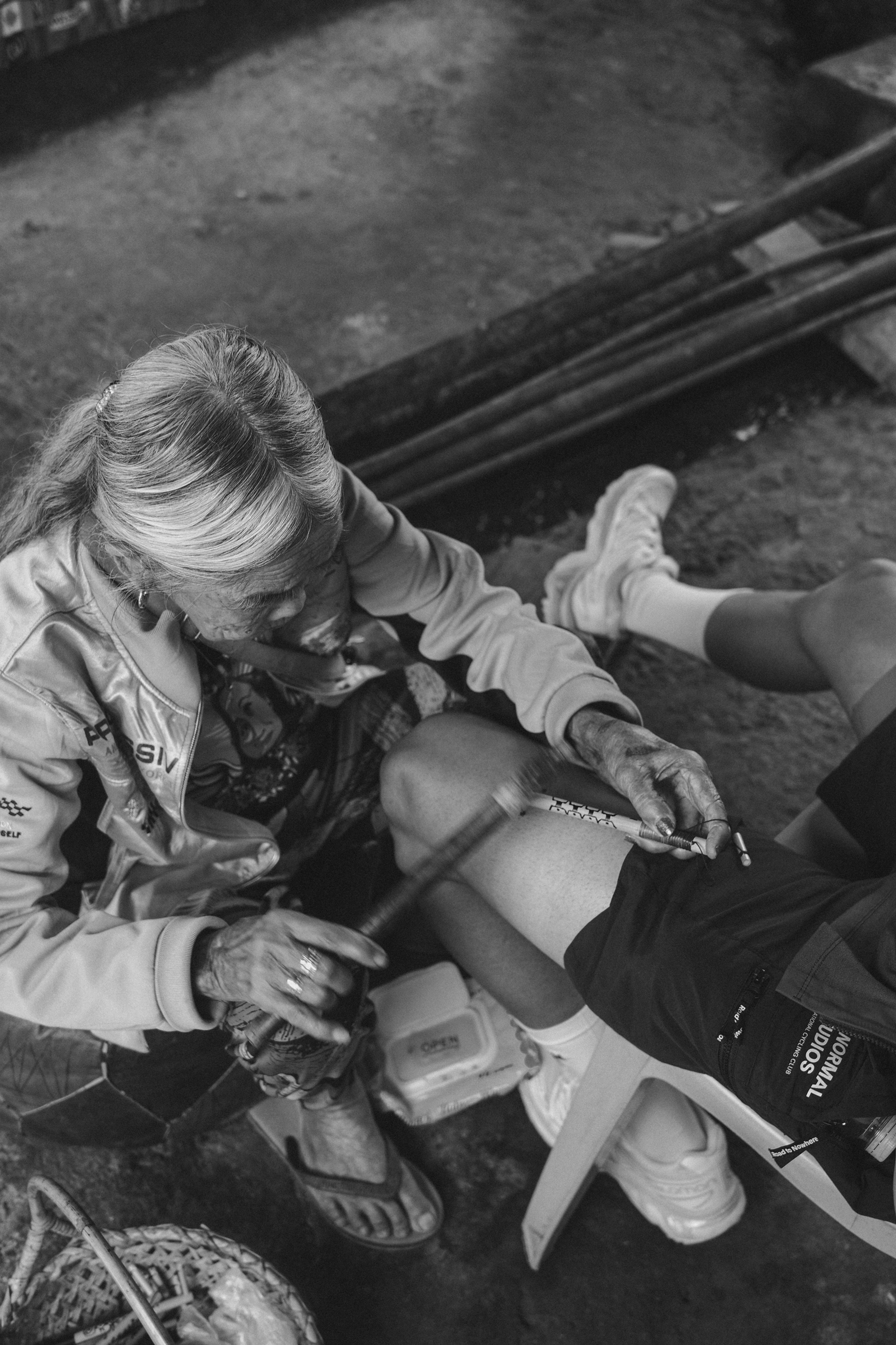 Cyclist applying leg warmers while sitting on bench with cycling gear nearby