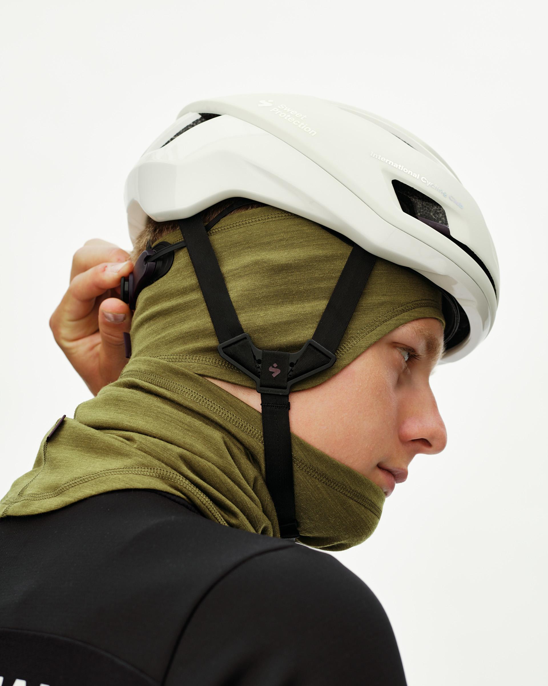 Khaki Green Essential Merino cycling headband worn as balaclava on model, side view with helmet over top