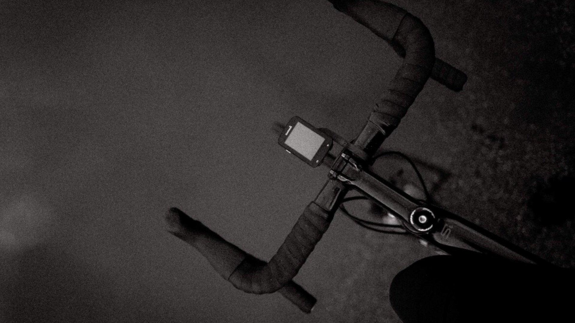 Black and white image of cycling pedal and shoe cleat mechanism on dark surface