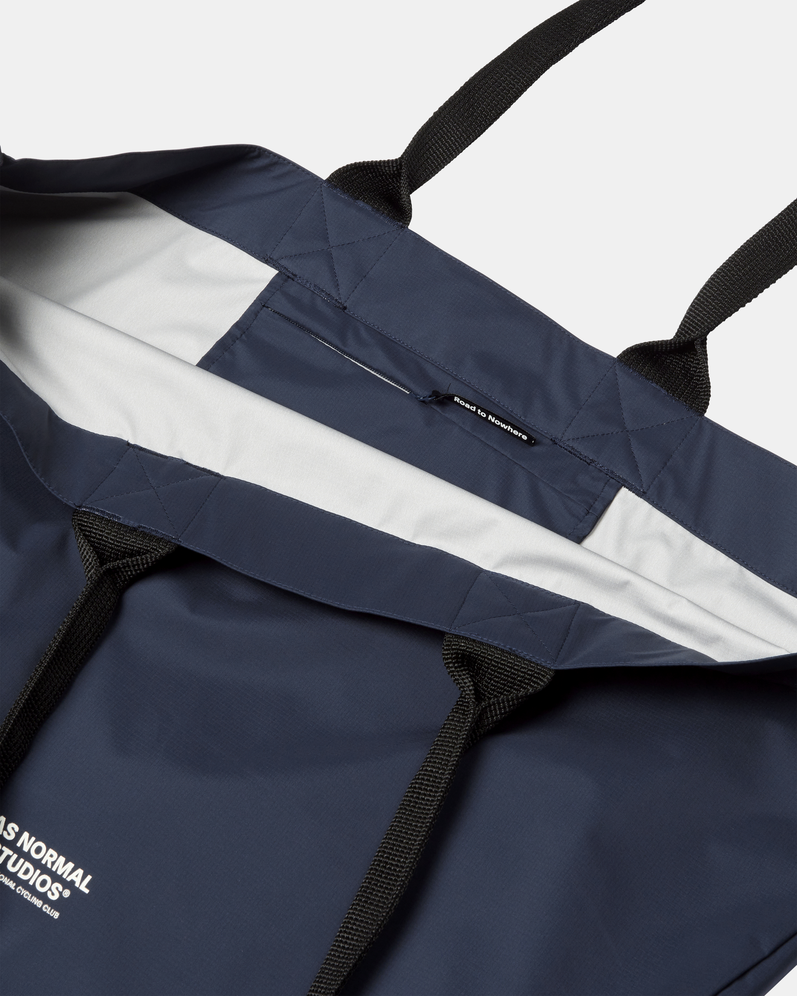 Navy Logo Shield tote bag, flat lay showing quilted panels and black webbing straps