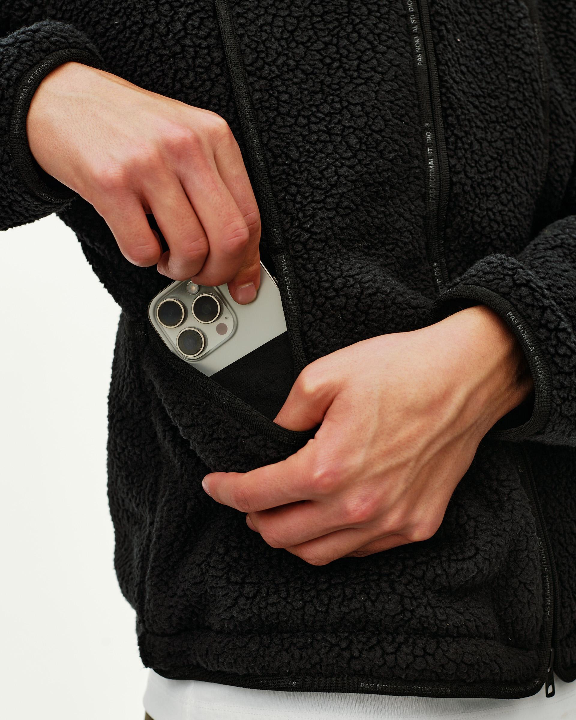 Black Off-Race Pile Fleece jacket, detail view of zip chest pocket with phone being inserted