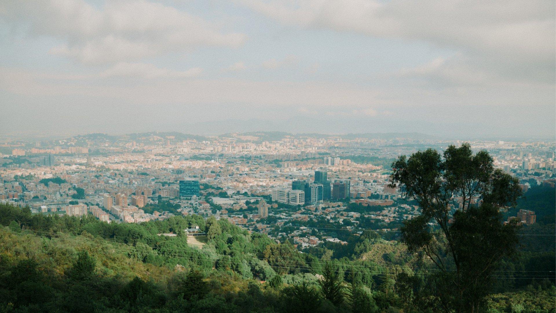 Panoramic view of Colombian city from hilltop overlooking urban landscape with mountains in distance