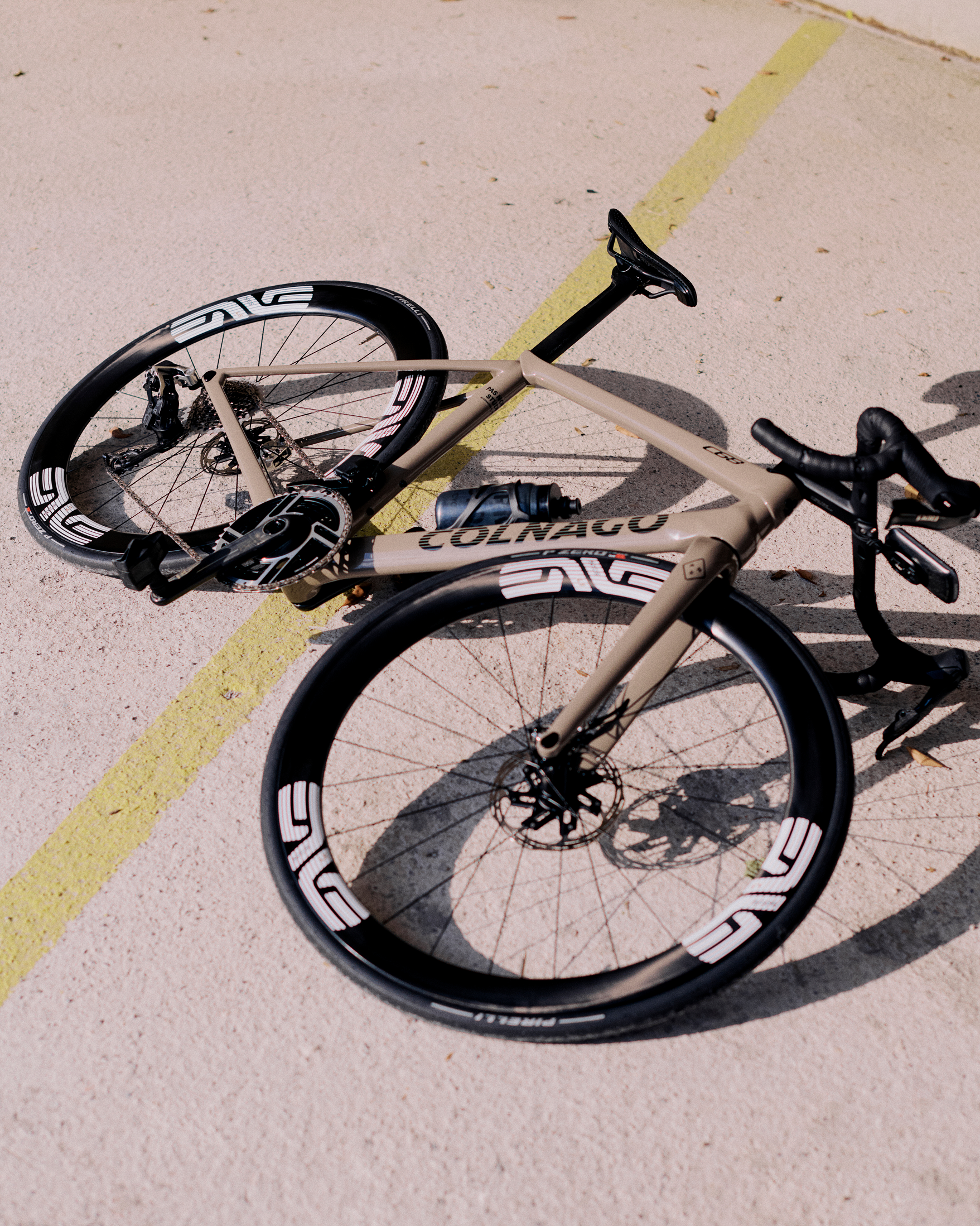 Colnago time trial bike with aerodynamic frame lying on pavement with yellow road marking