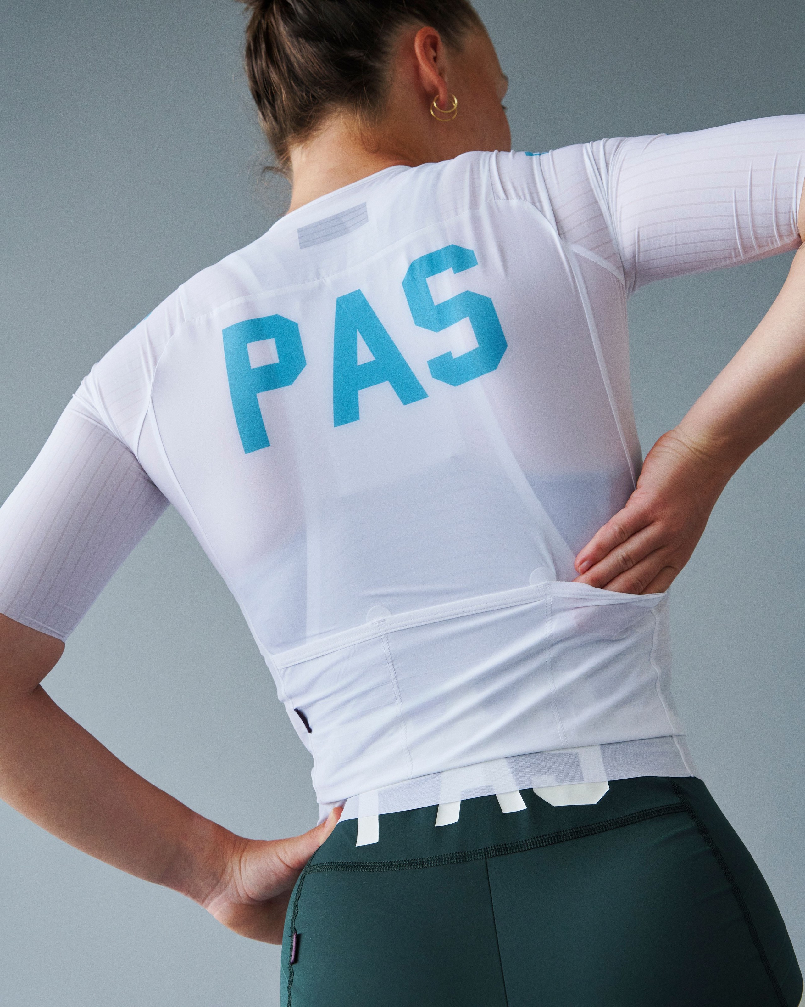 White PAS Mechanism Pro cycling jersey on model, rear view with blue PAS back print
