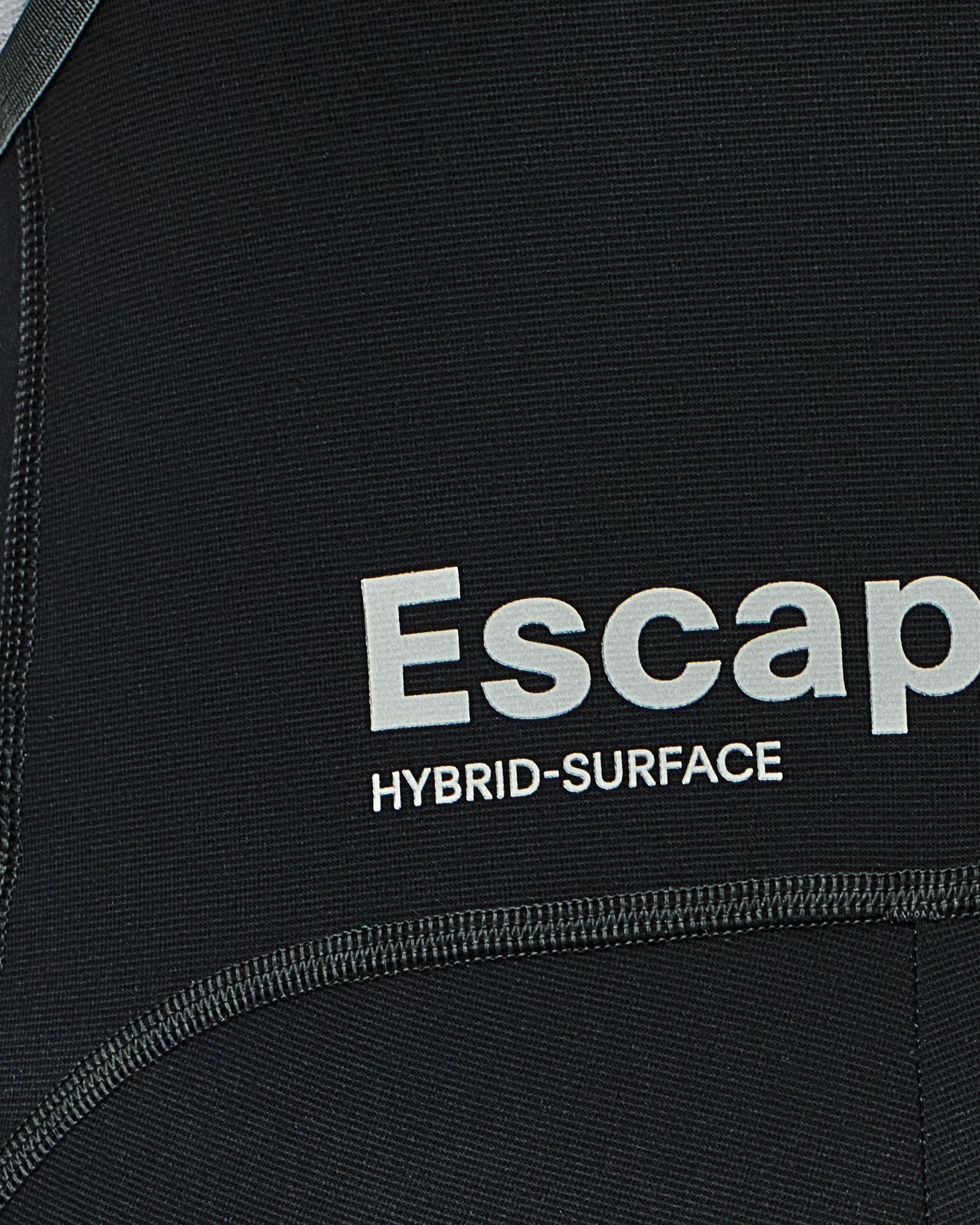Dark structured fabric with "Escape Hybrid-Surface" text and flatlock seams providing abrasion resistance