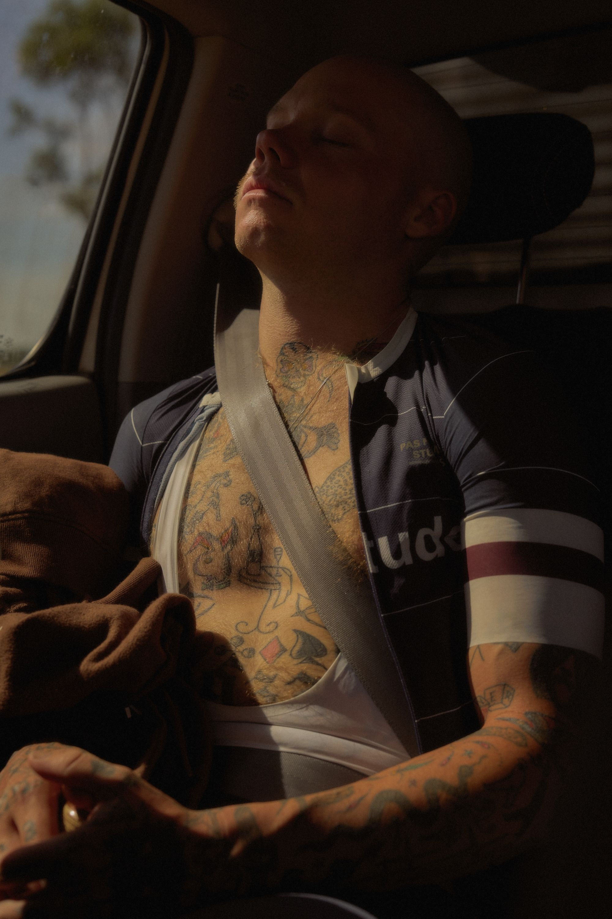 Model wearing black cycling jersey with white side panels relaxing in car interior