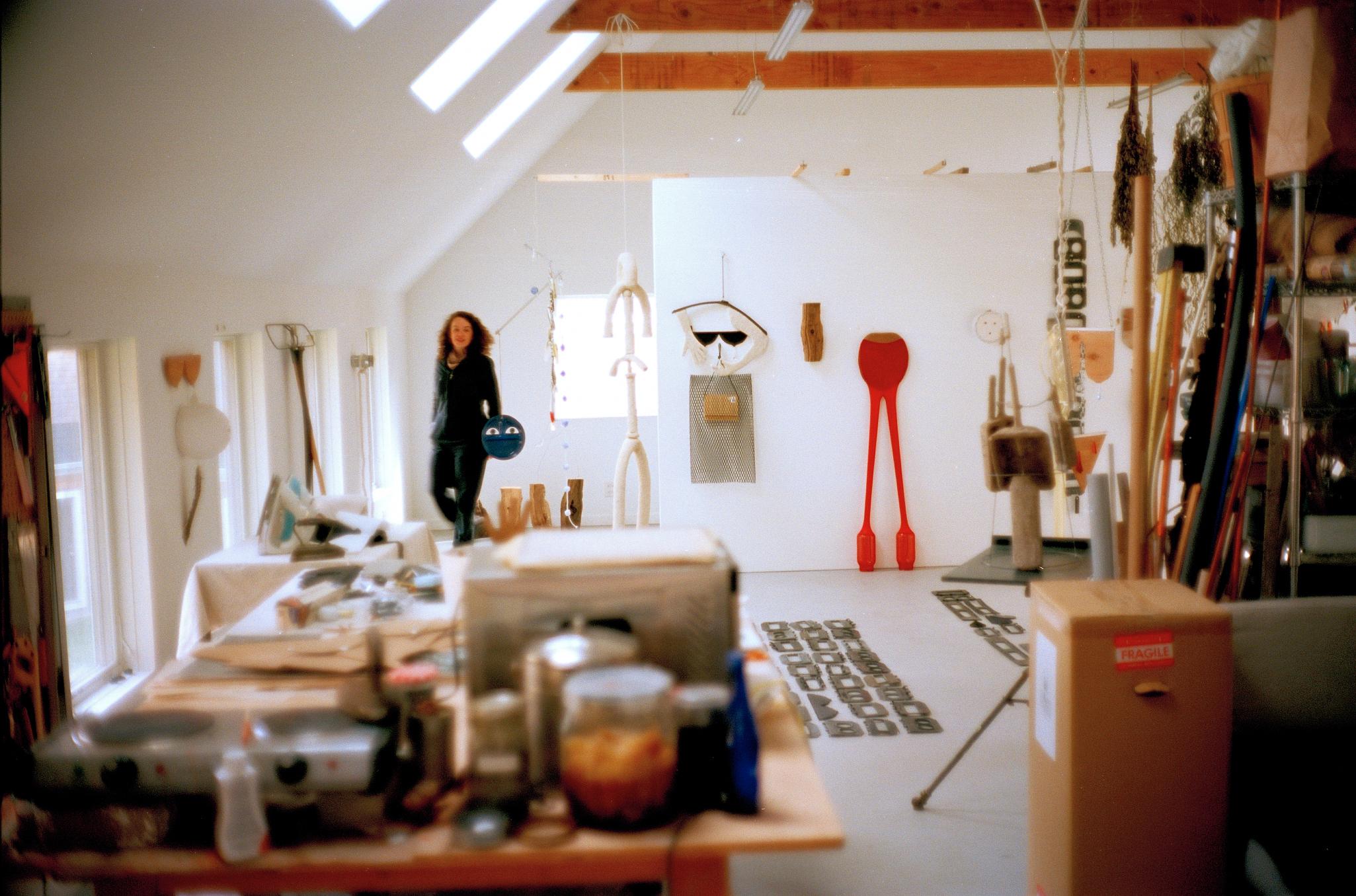 Creative workshop space with person in black clothing among art supplies and wall-mounted objects