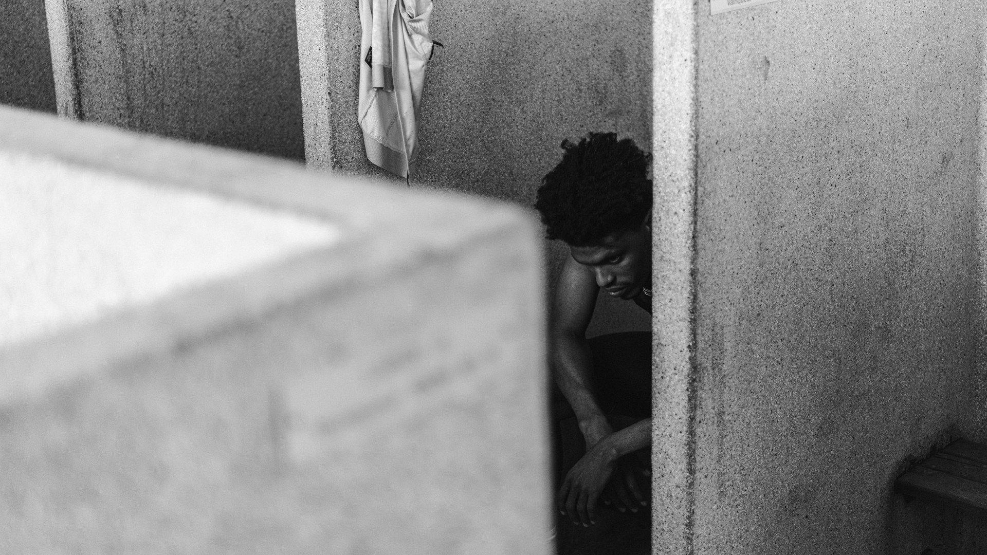 Model in concrete architectural space with dramatic lighting and shadows, black and white photography
