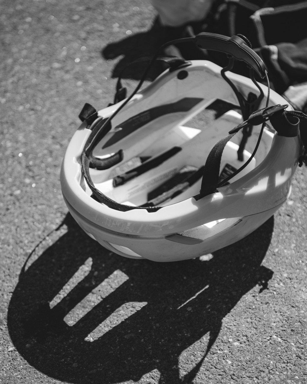 White cycling helmet with adjustment straps on cobblestone pavement in black and white