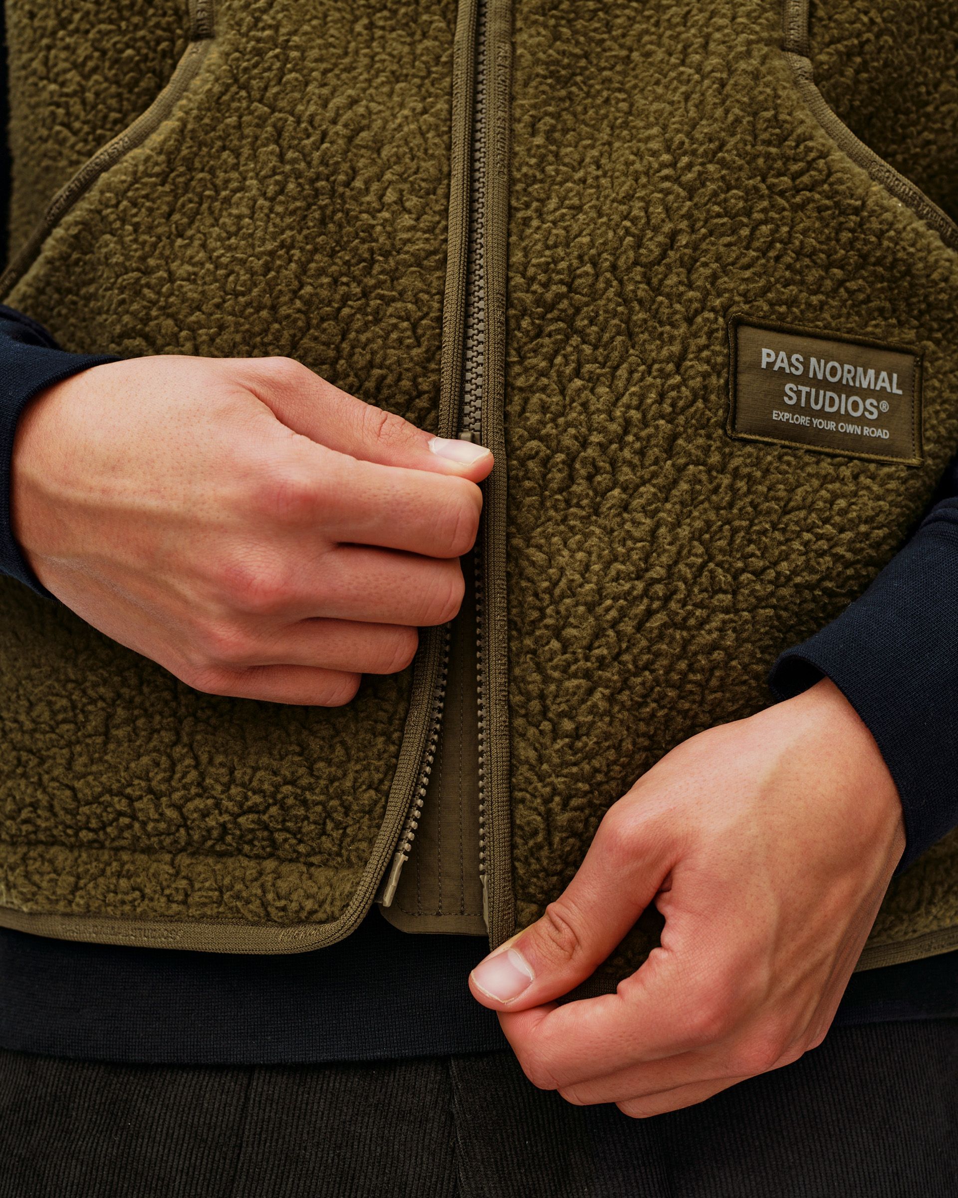Deep Olive Off-Race Pile Fleece vest, front detail on model with full zip and branded chest patch