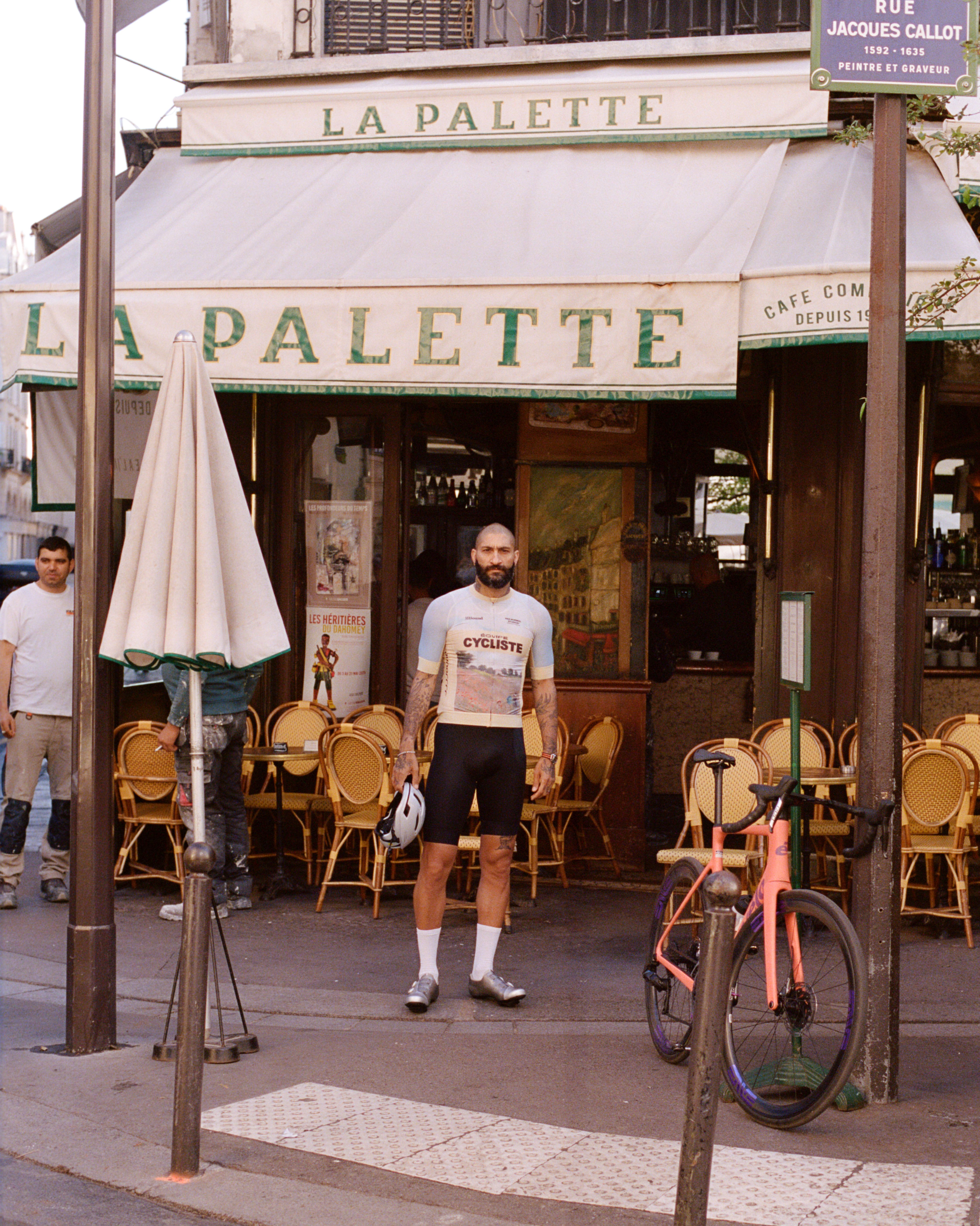 Model wearing white cycling t-shirt with vintage graphics and black shorts outside French cafe