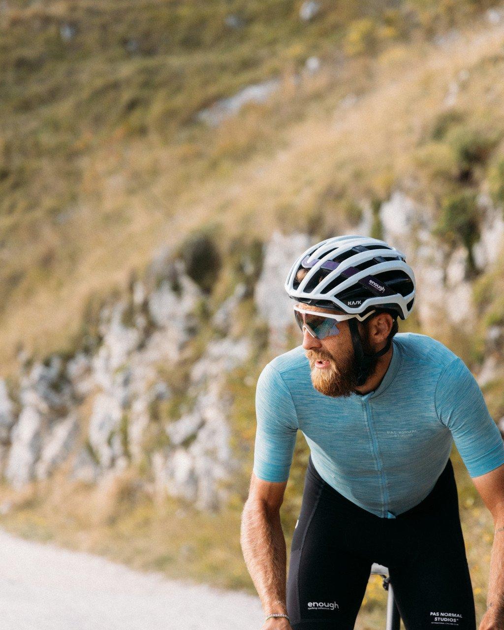 Model wearing blue textured cycling jersey with black shorts, white helmet, outdoors on road