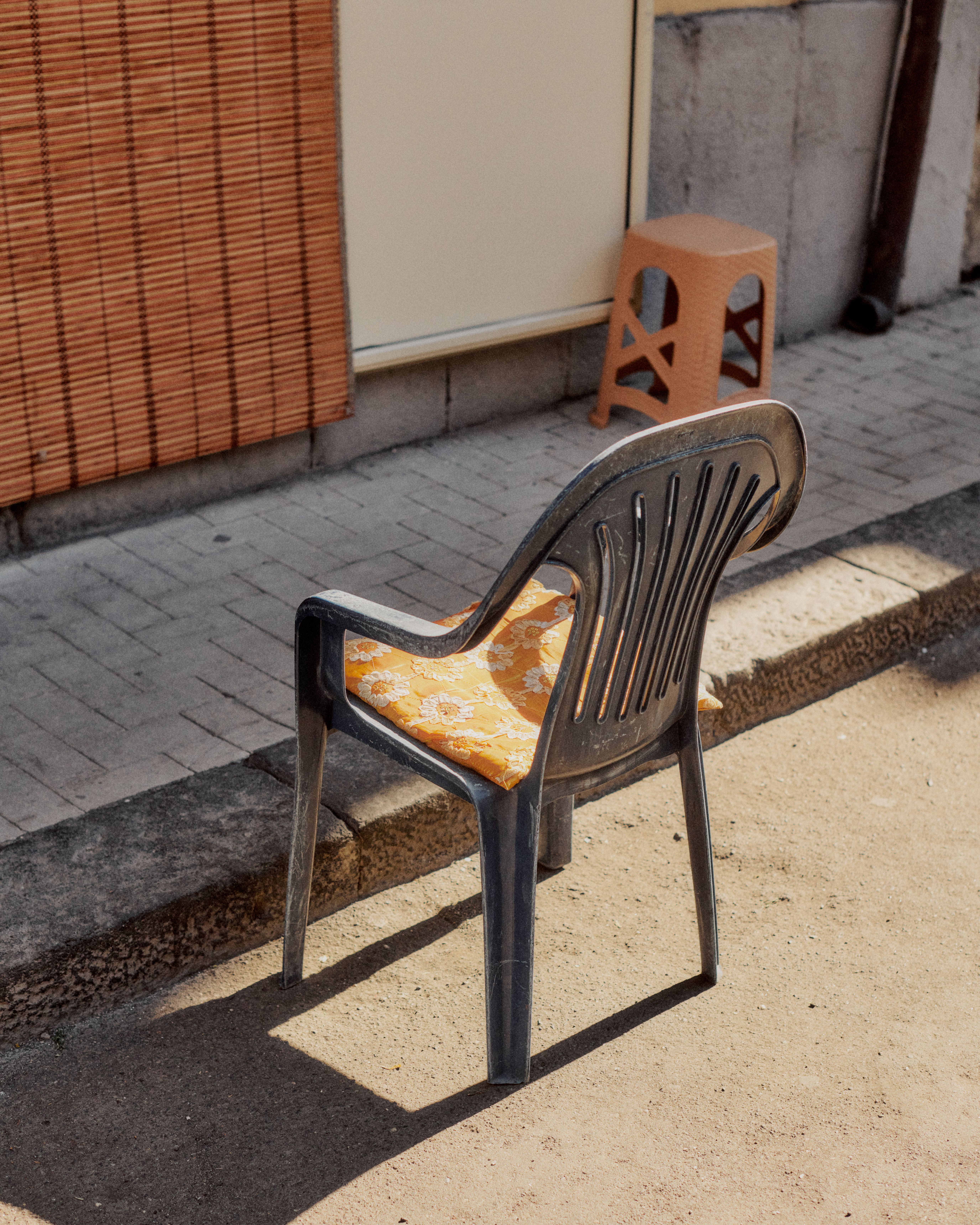 Orange cycling kit draped over plastic chair on urban street in Sicily