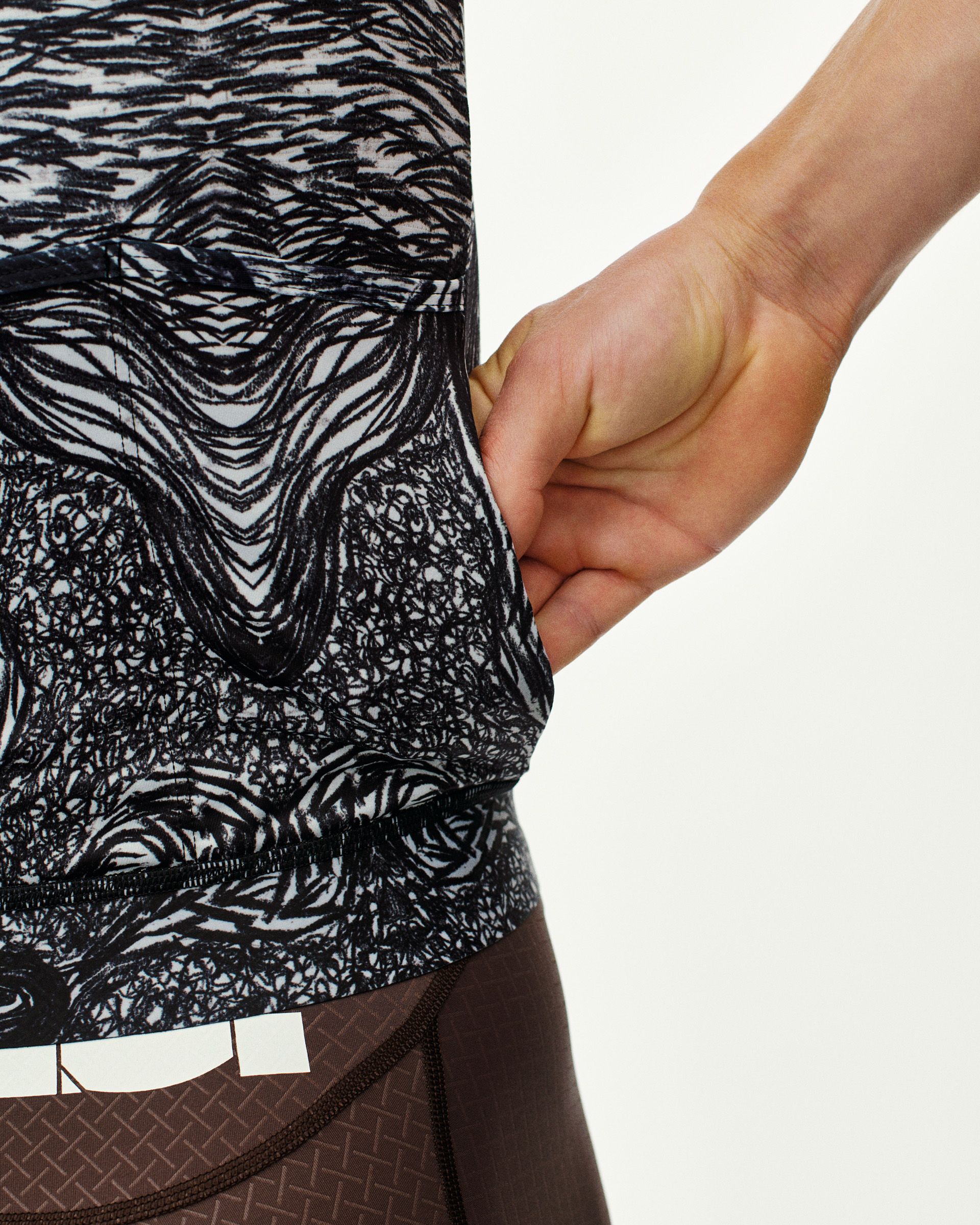 Iron Grey T.K.O. Mechanism cycling jersey, side detail on model showing rear pocket opening with abstract print