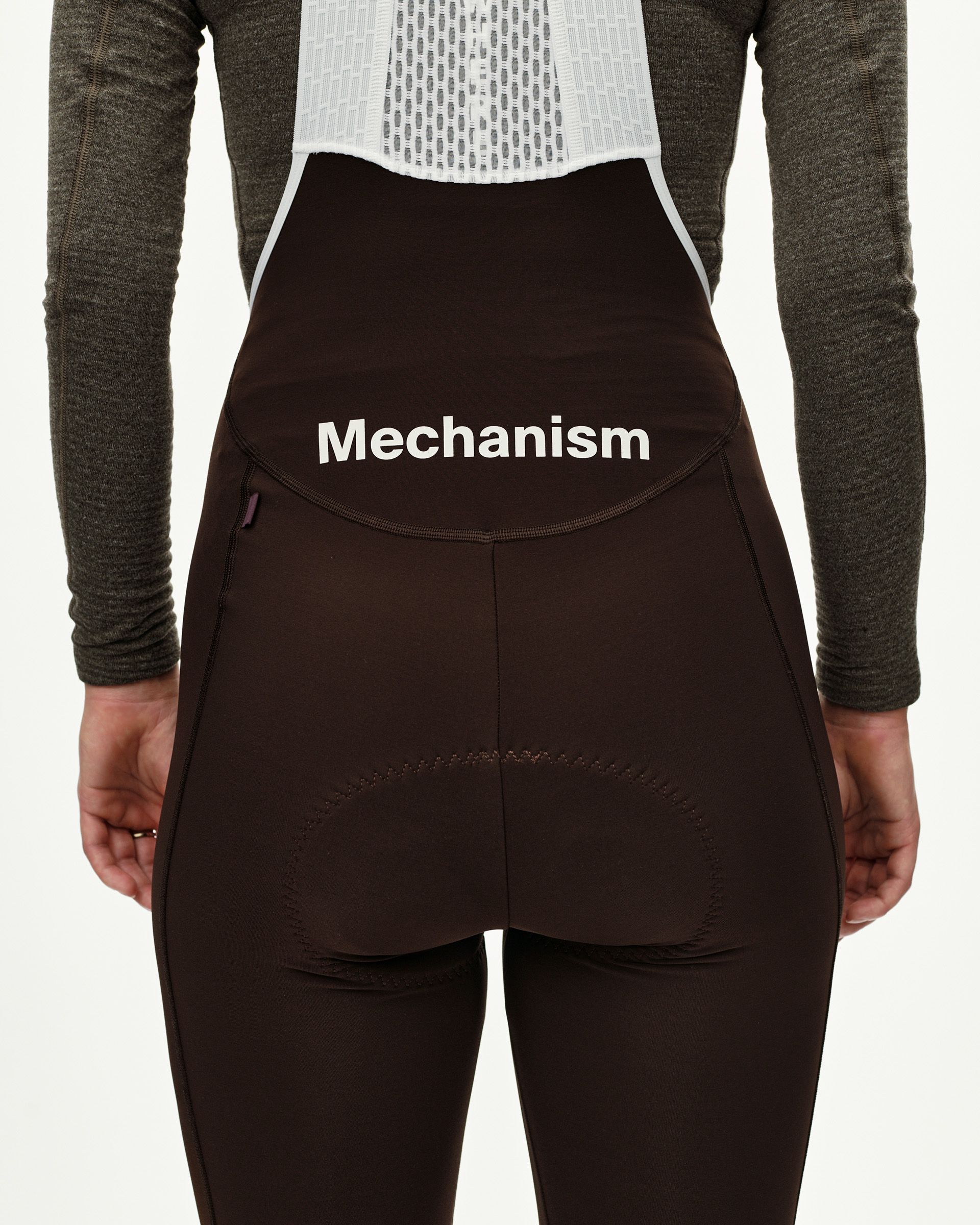 Dark Coffee Mechanism Thermal Long cycling bibs on model, rear view with white logo print and back pocket