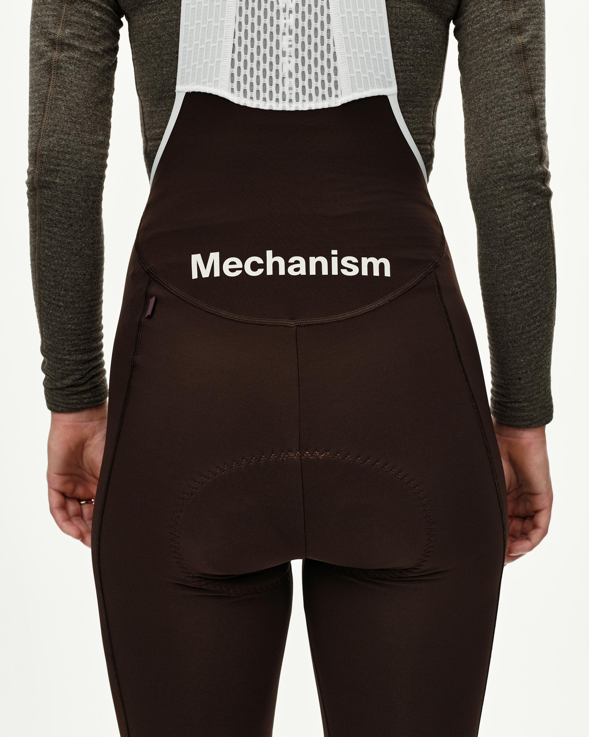 Dark Coffee Mechanism Thermal Long cycling bibs on model, rear view with white logo print and back pocket