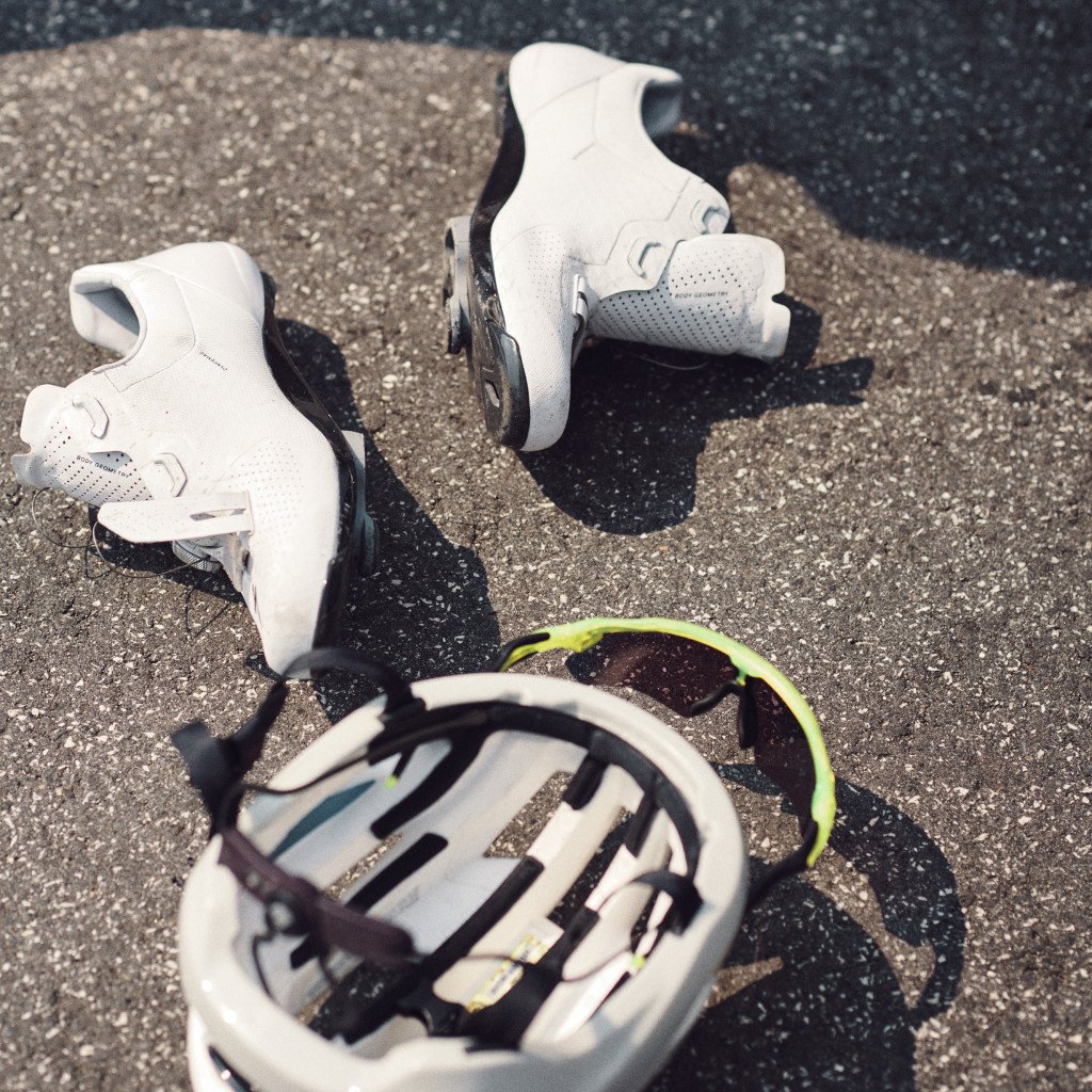 White cycling shoes and helmet with green accents on asphalt road surface