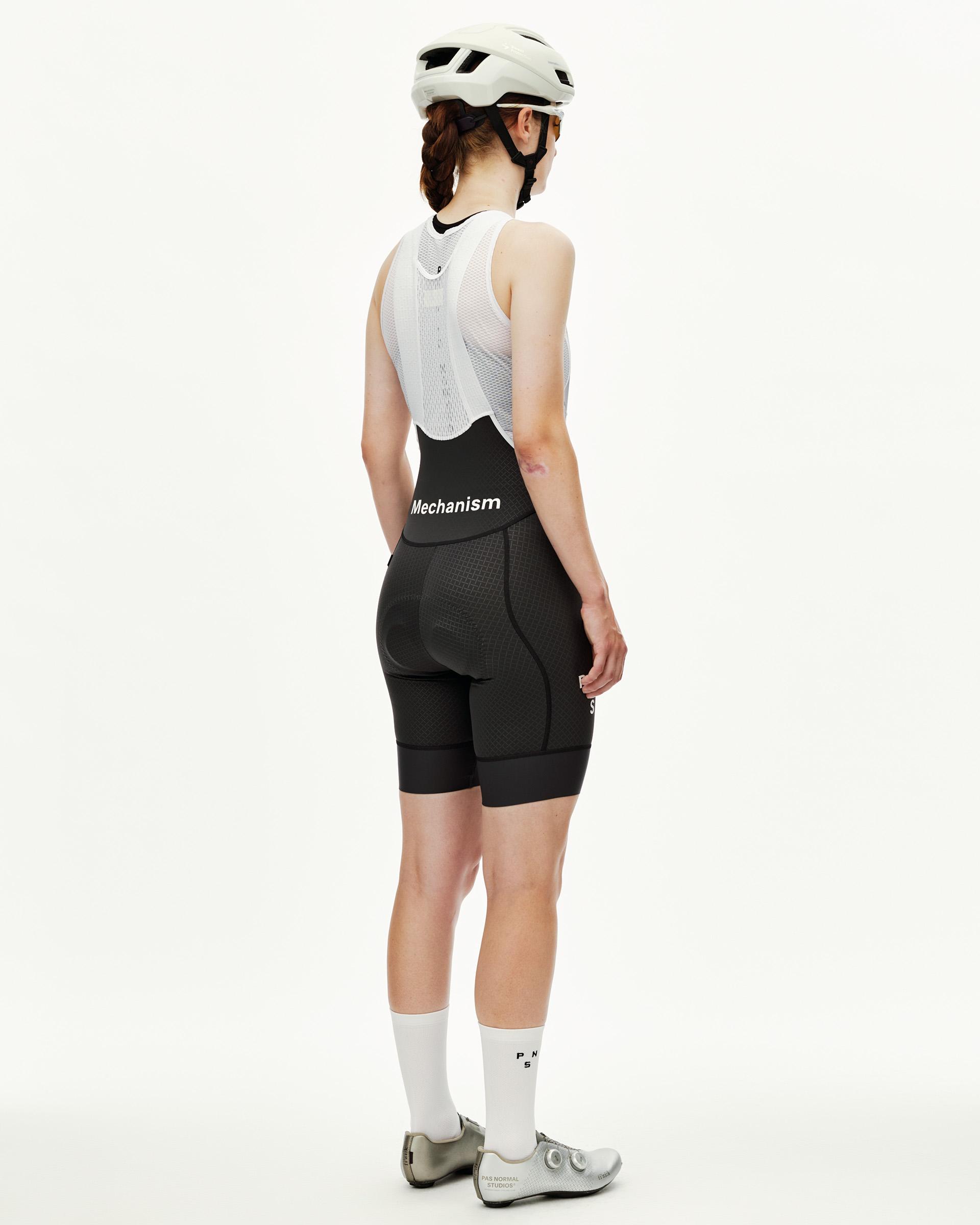 Dark Navy Mechanism women's cycling bibs on model, rear view with white mesh bib straps and waistband logo