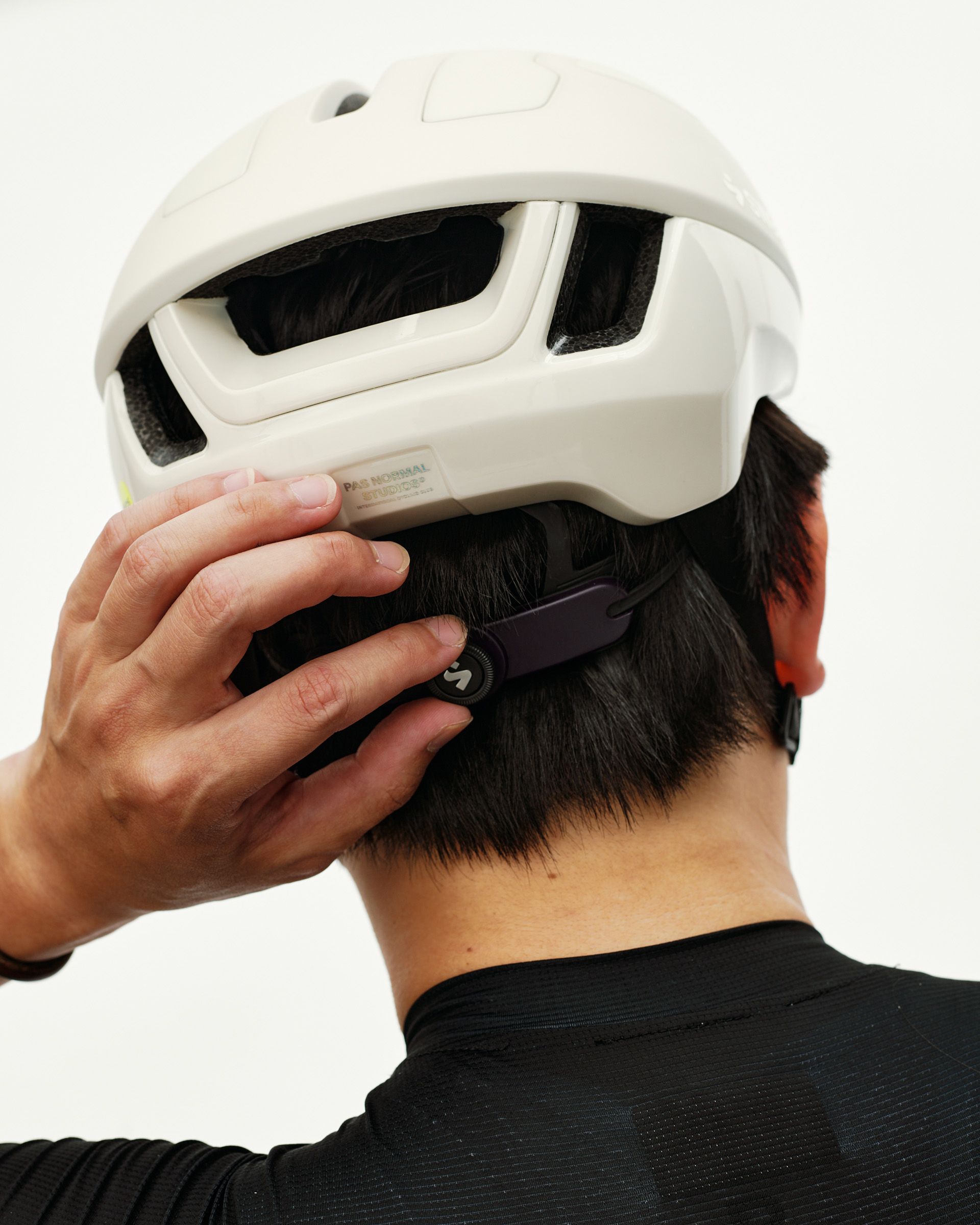 Off White Sweet Protection Falconer Aero 2Vi MIPS Round Fit cycling helmet, rear view on model adjusting fit dial