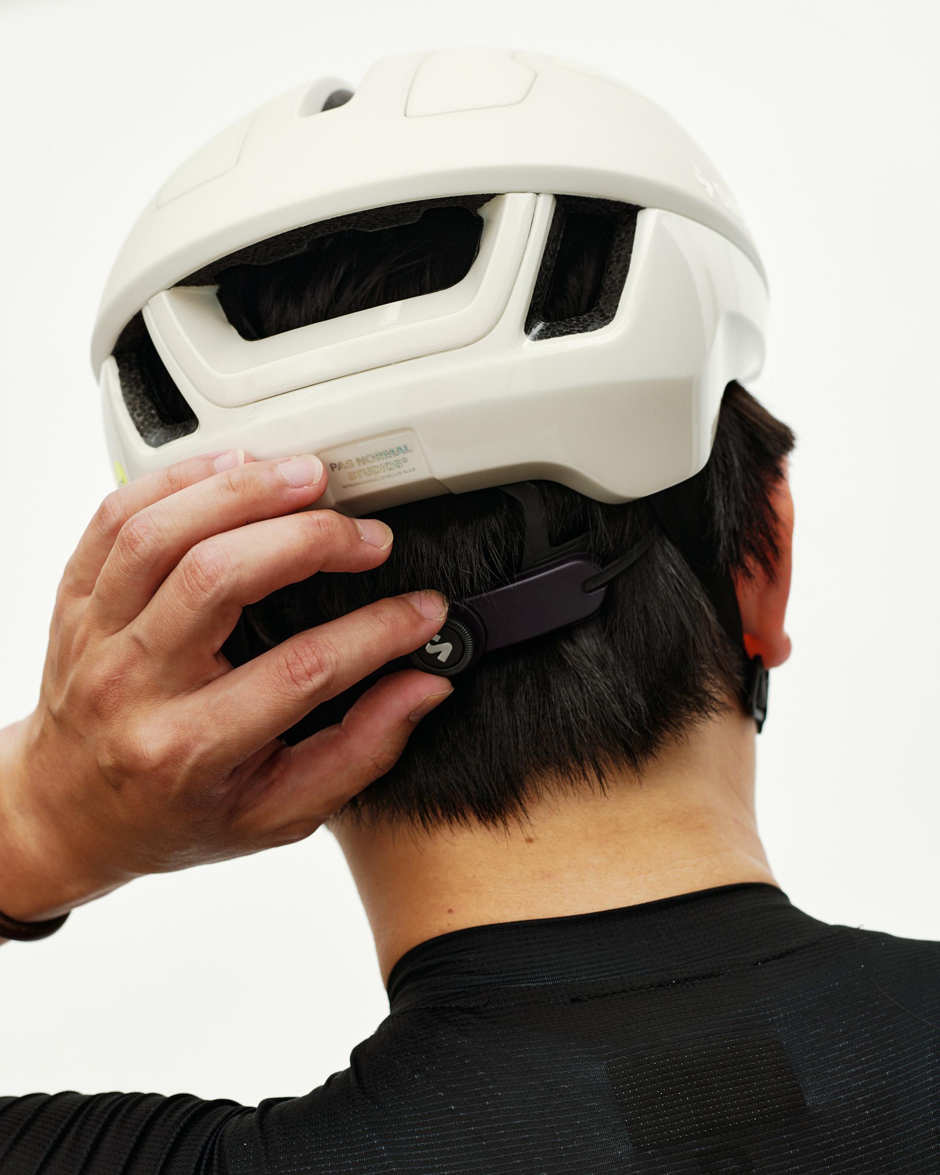 Off White Sweet Protection Falconer Aero 2Vi MIPS Round Fit cycling helmet, rear view on model adjusting fit dial