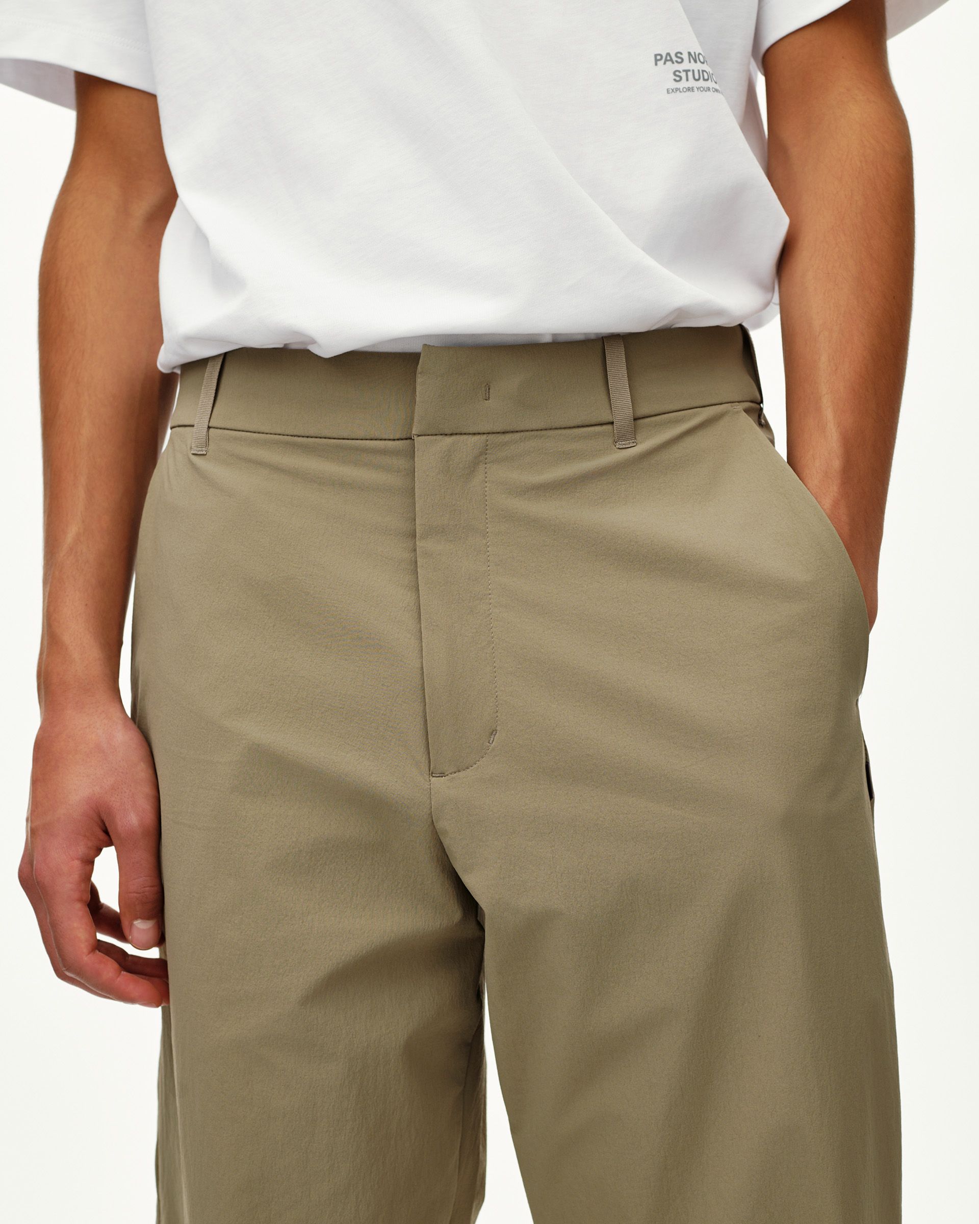 Dusty Earth khaki Off-Race Tech pants on model, front detail view with clean waistband and hidden fly