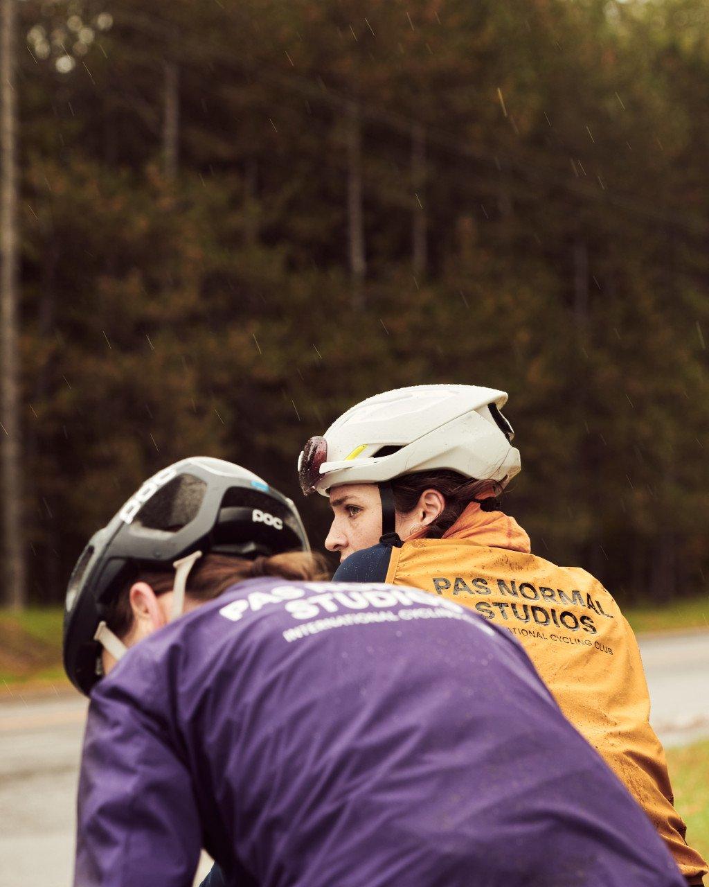 Models wearing orange and purple cycling jackets with back branding in rain