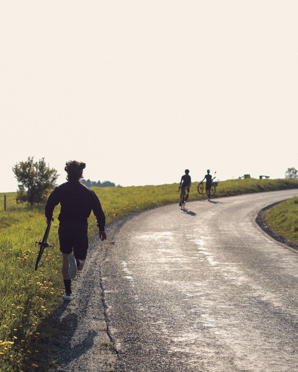 Cyclists on rural road through countryside with wildflowers and rolling hills