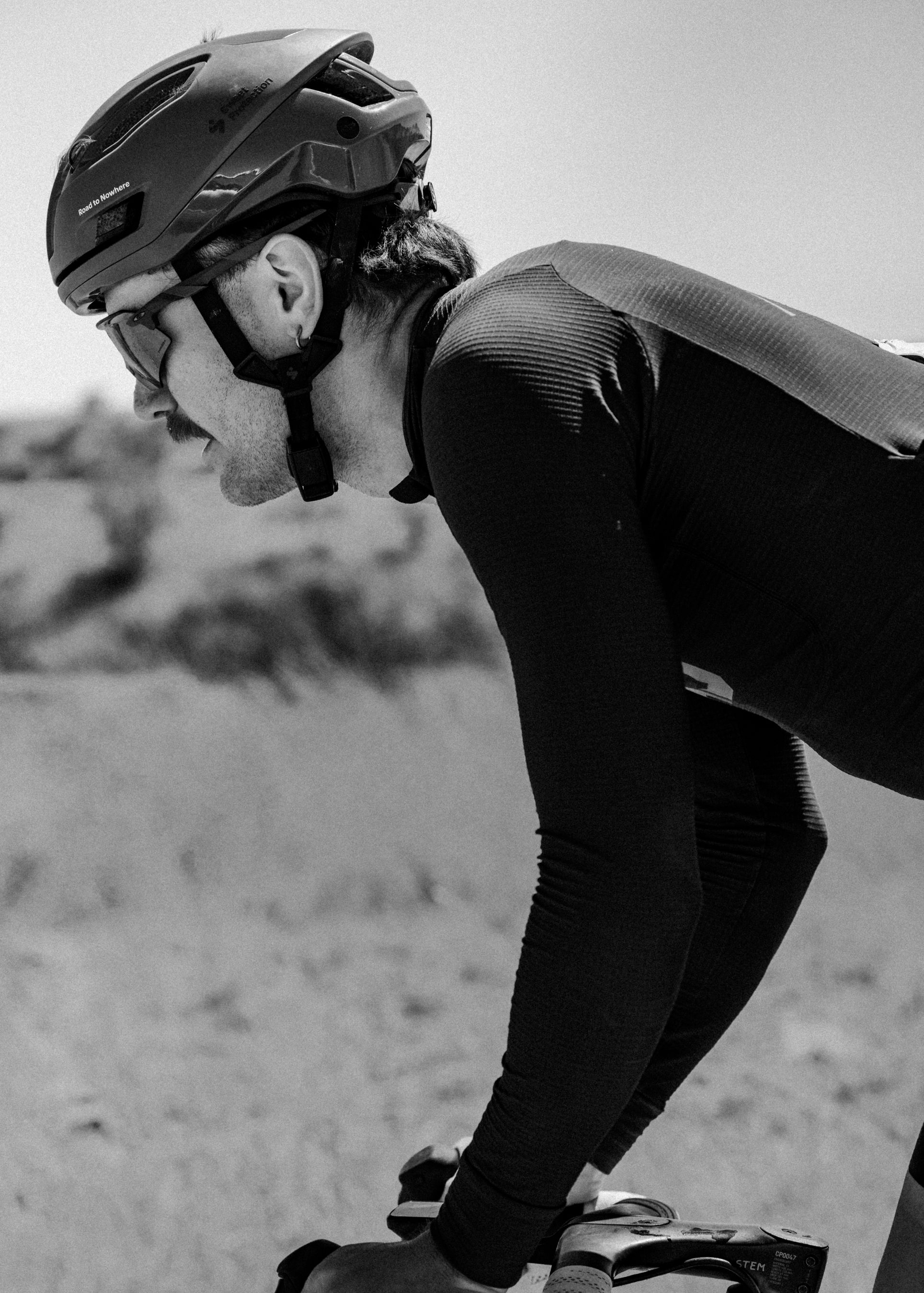 Model wearing dark cycling skinsuit and helmet in aerodynamic position during training